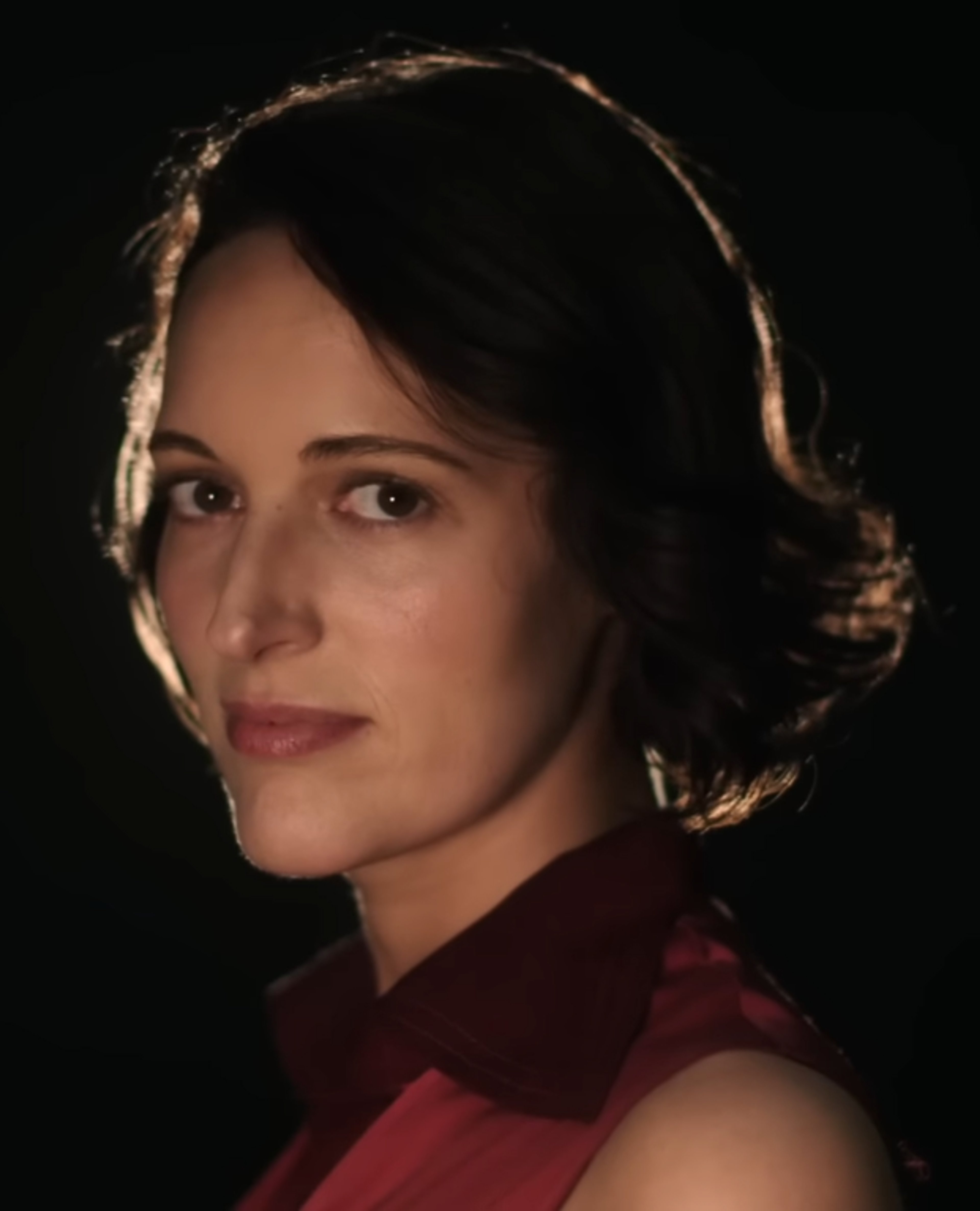 A woman with dark curly hair wearing a red blouse