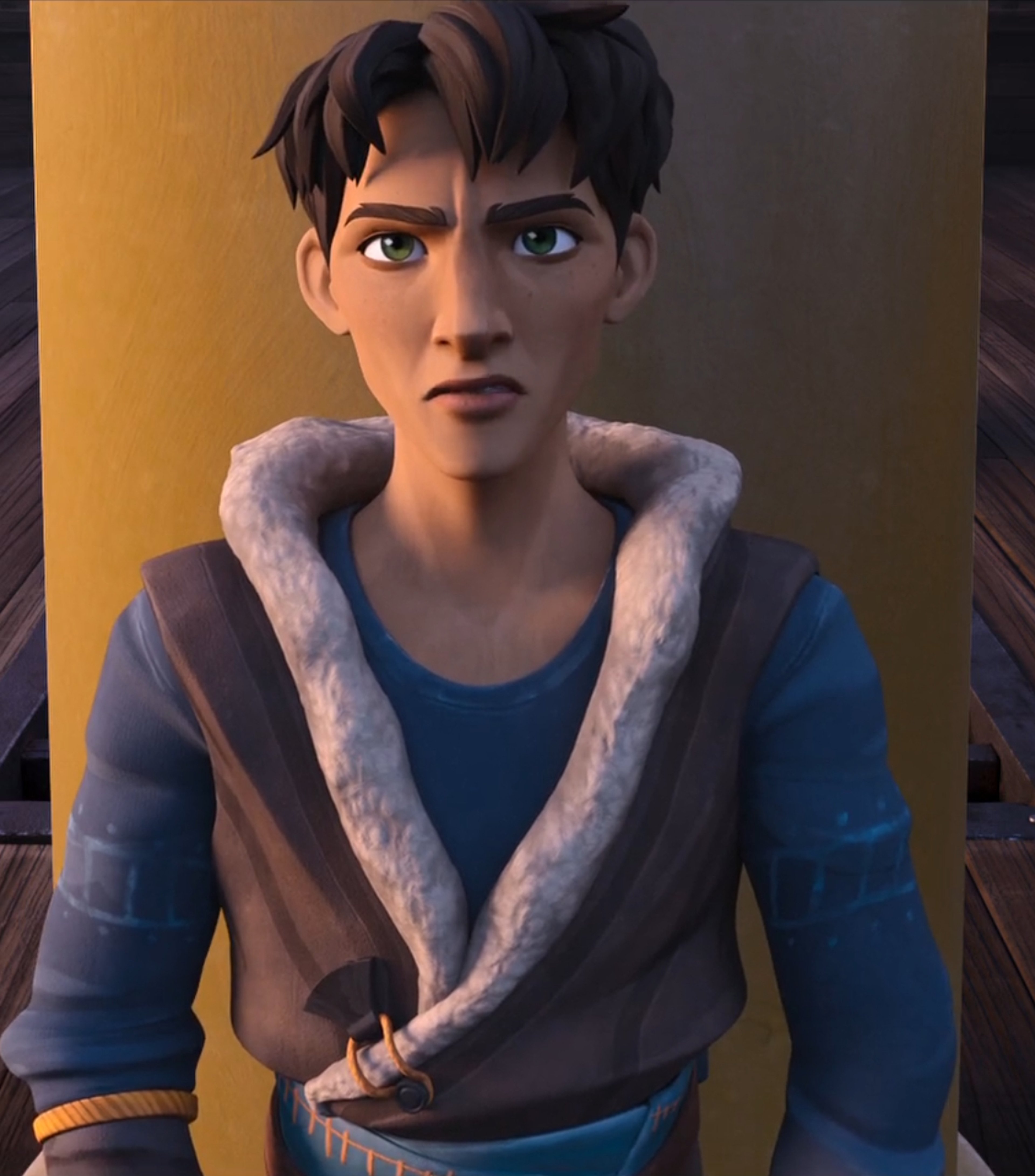 A young man with short dark hair and green eyes wearing a blue shirt with a fur collar