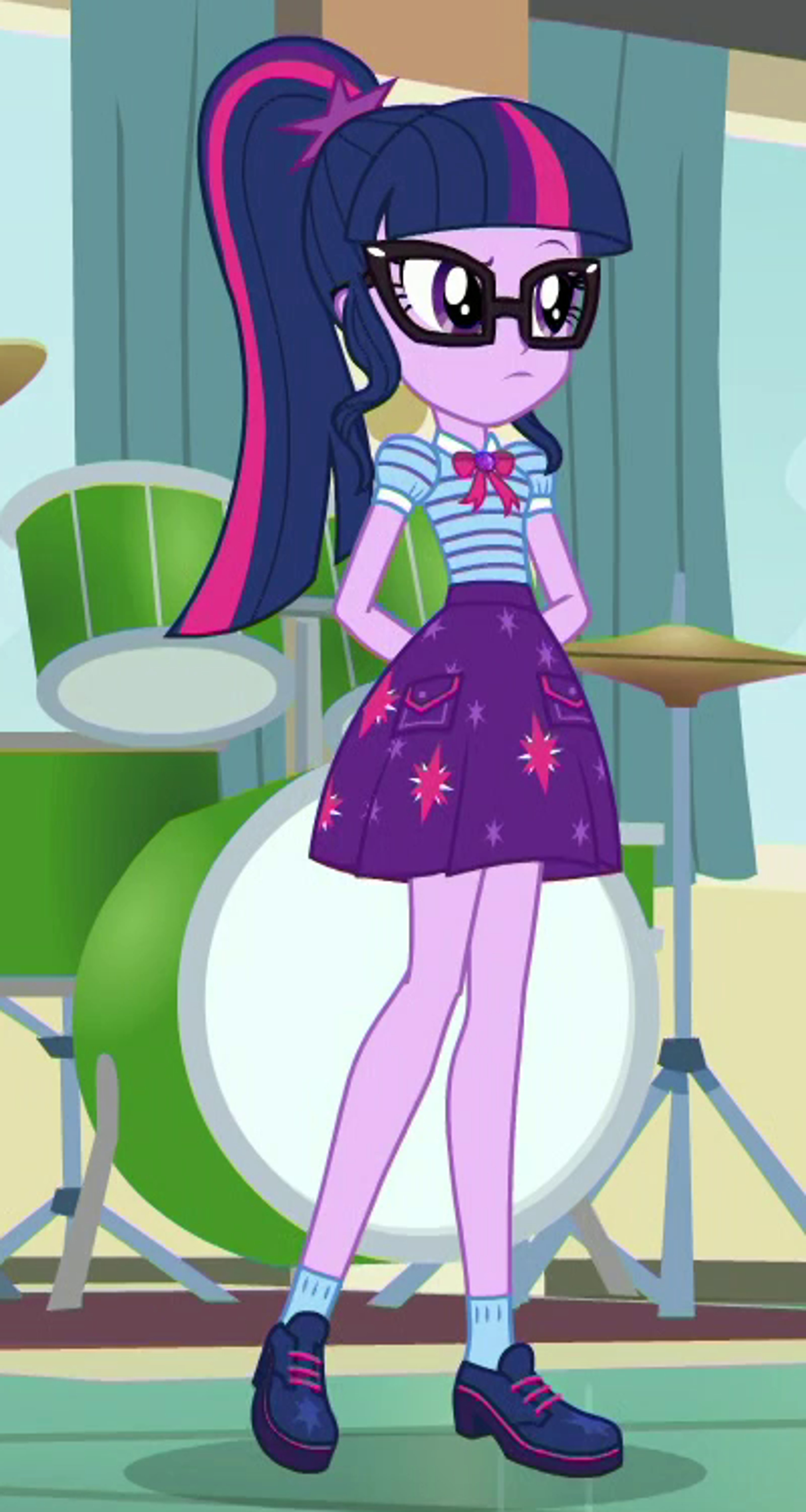 A teenage girl with glasses and dark blue hair with purple and pink streaks, wearing a purple dress with a star pattern, standing in an academic setting.