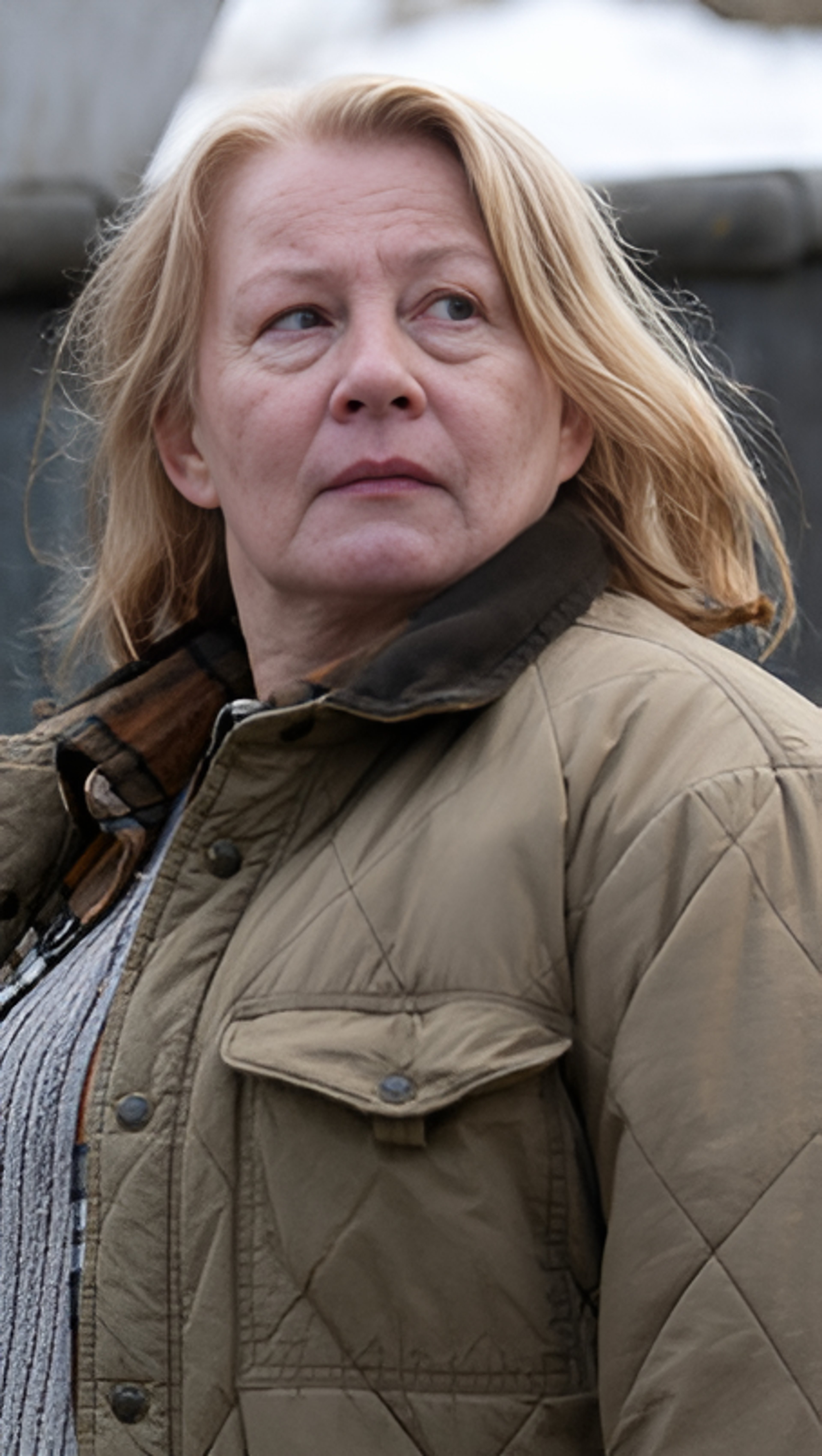 A middle-aged woman with blonde hair wearing a beige jacket