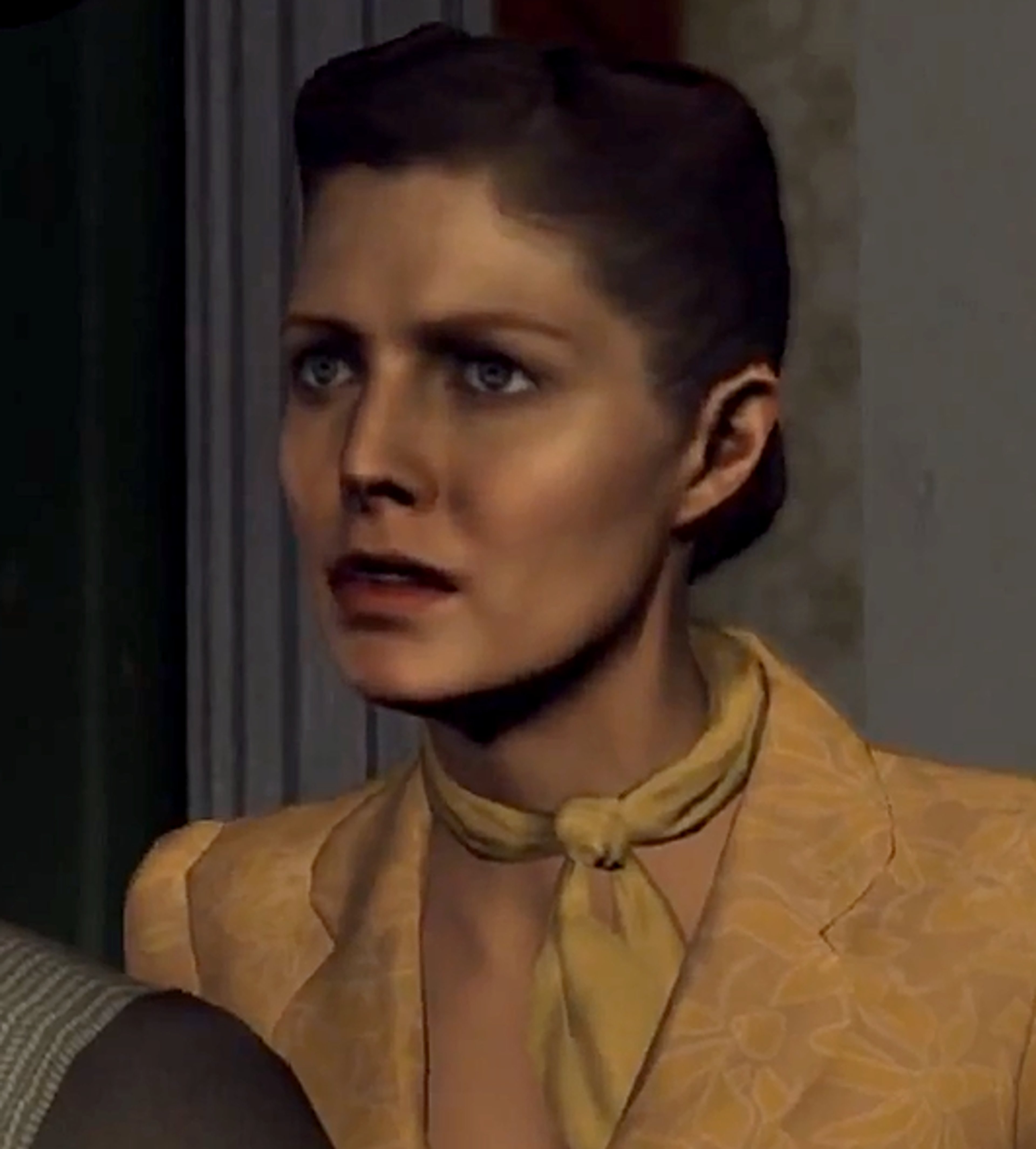 A woman with dark hair wearing a yellow coat in a dimly lit indoor setting