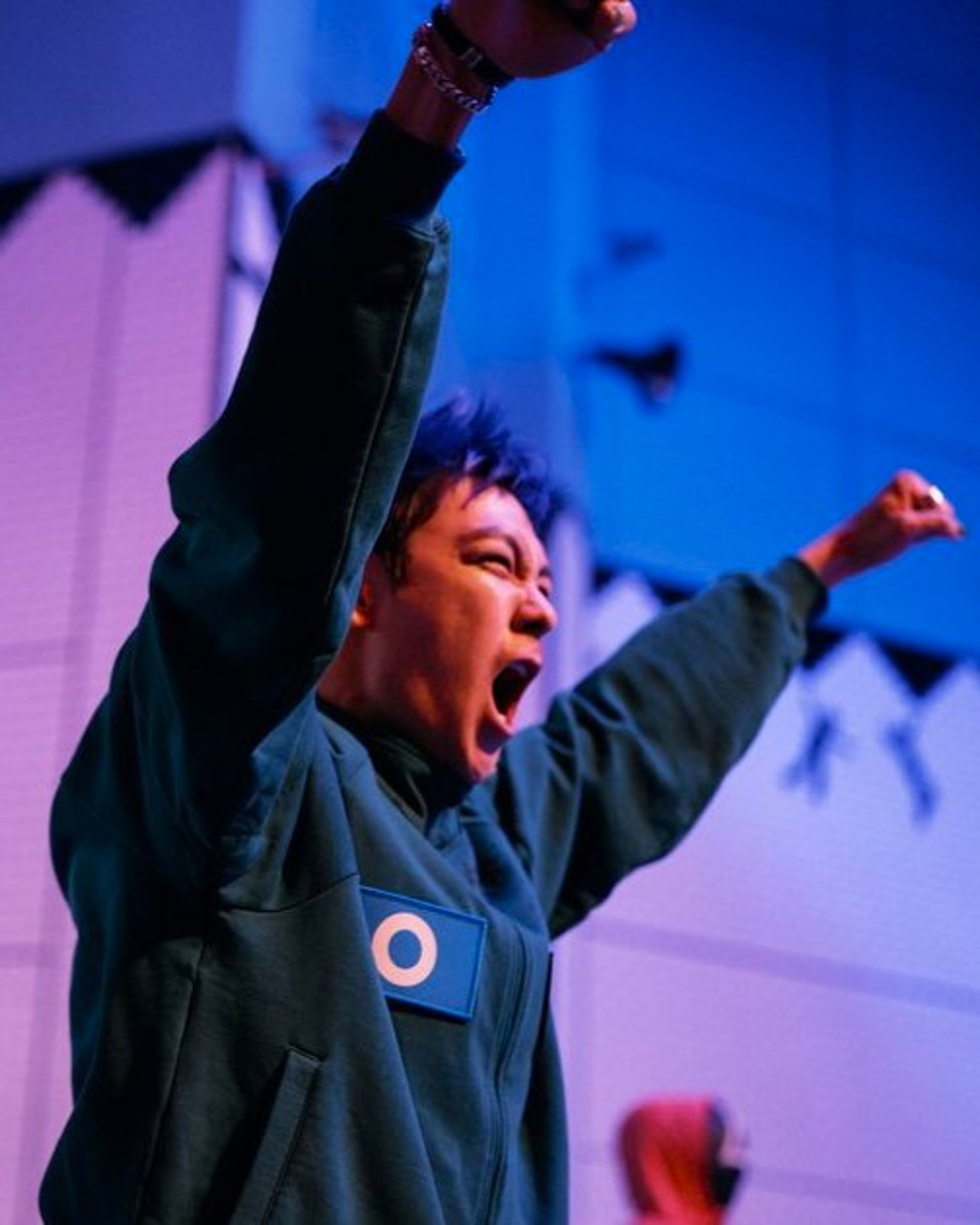 A large, muscular man with a shaved head and tattoos, shouting or yelling with an intense expression.