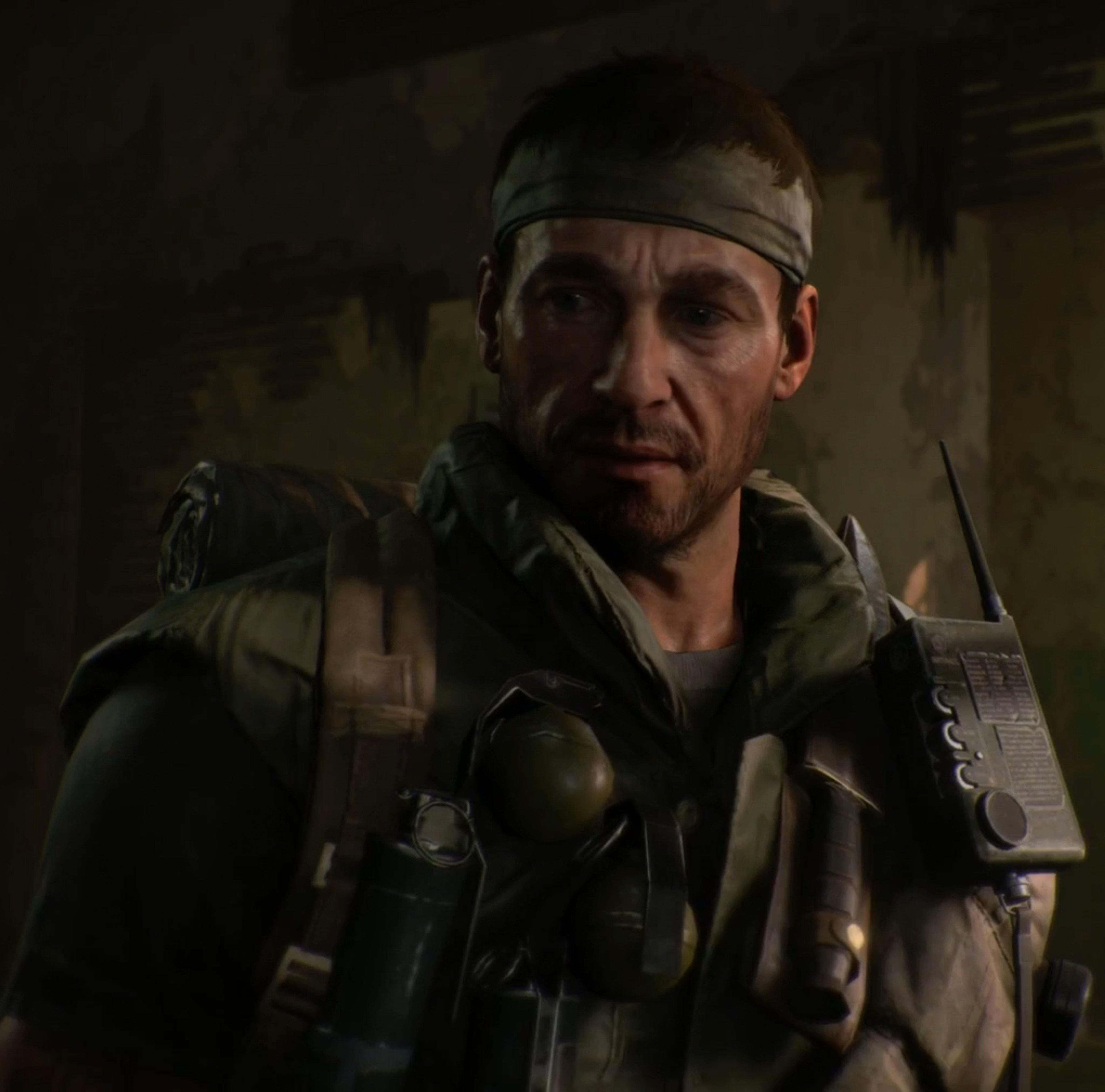A grizzled, middle-aged man in military-style clothing with a stern expression