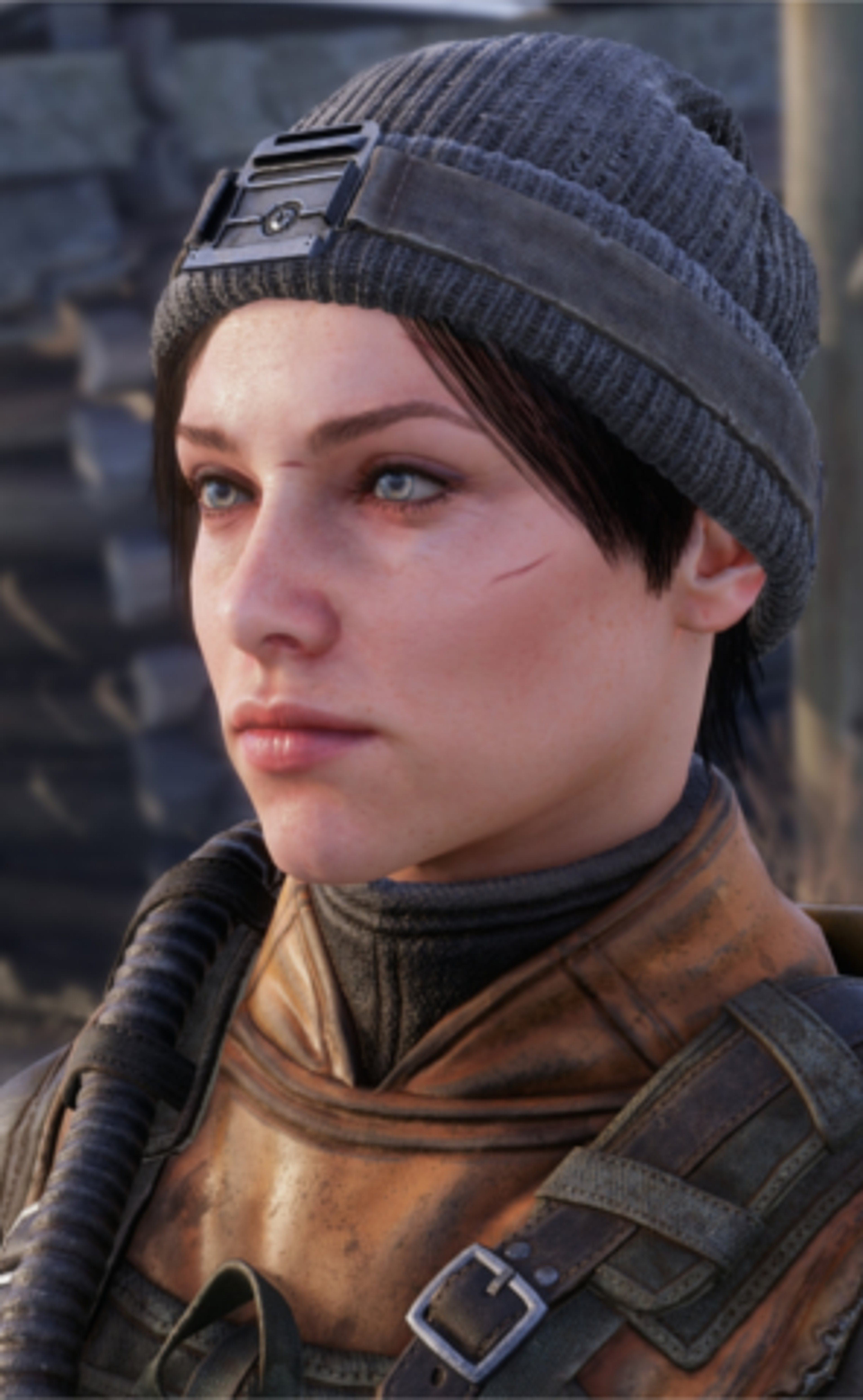 A young woman with dark hair and blue eyes wearing a military-style jacket and knit cap, with a serious expression on her face.