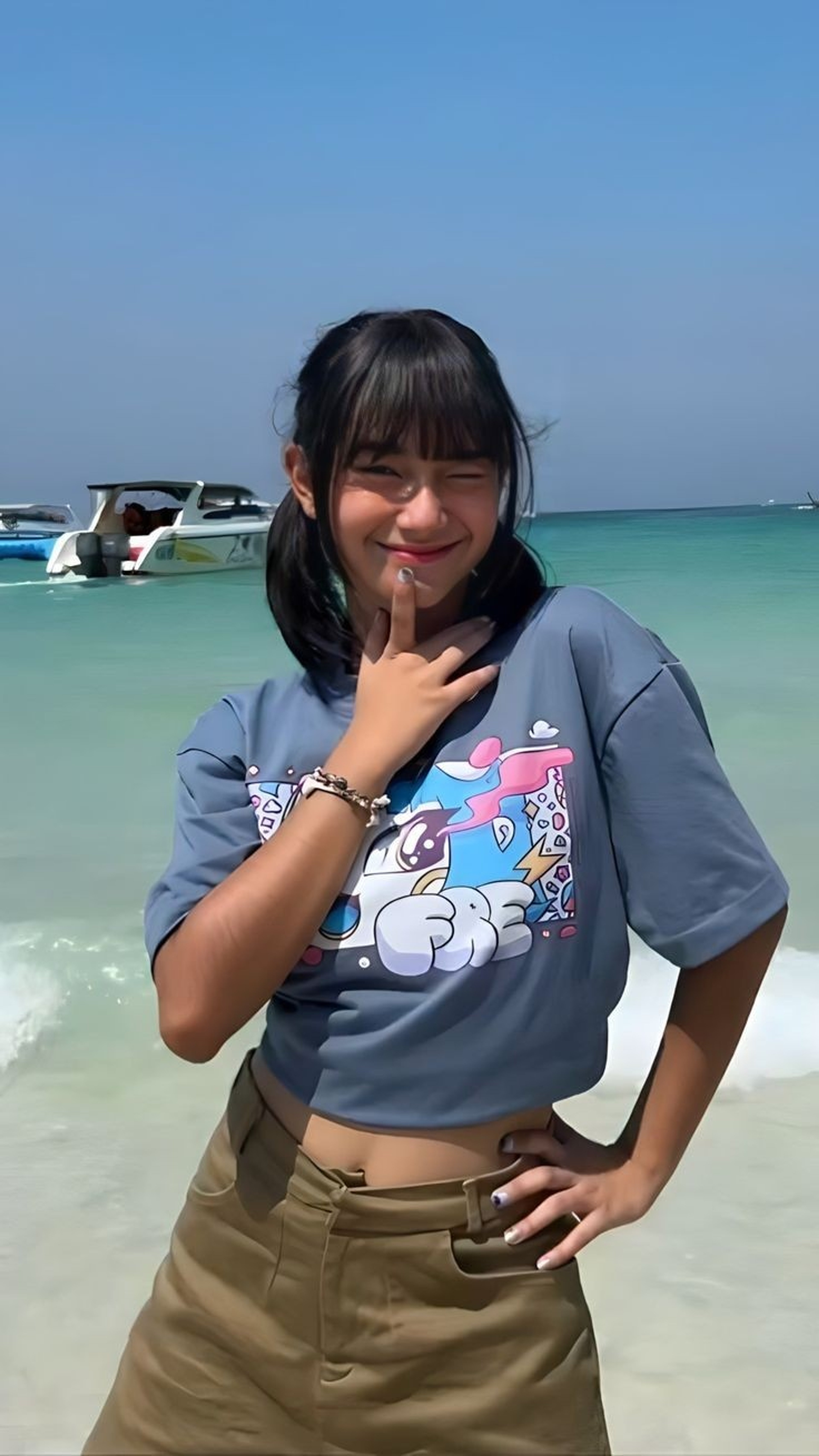 A young woman with long dark hair smiling on a beach