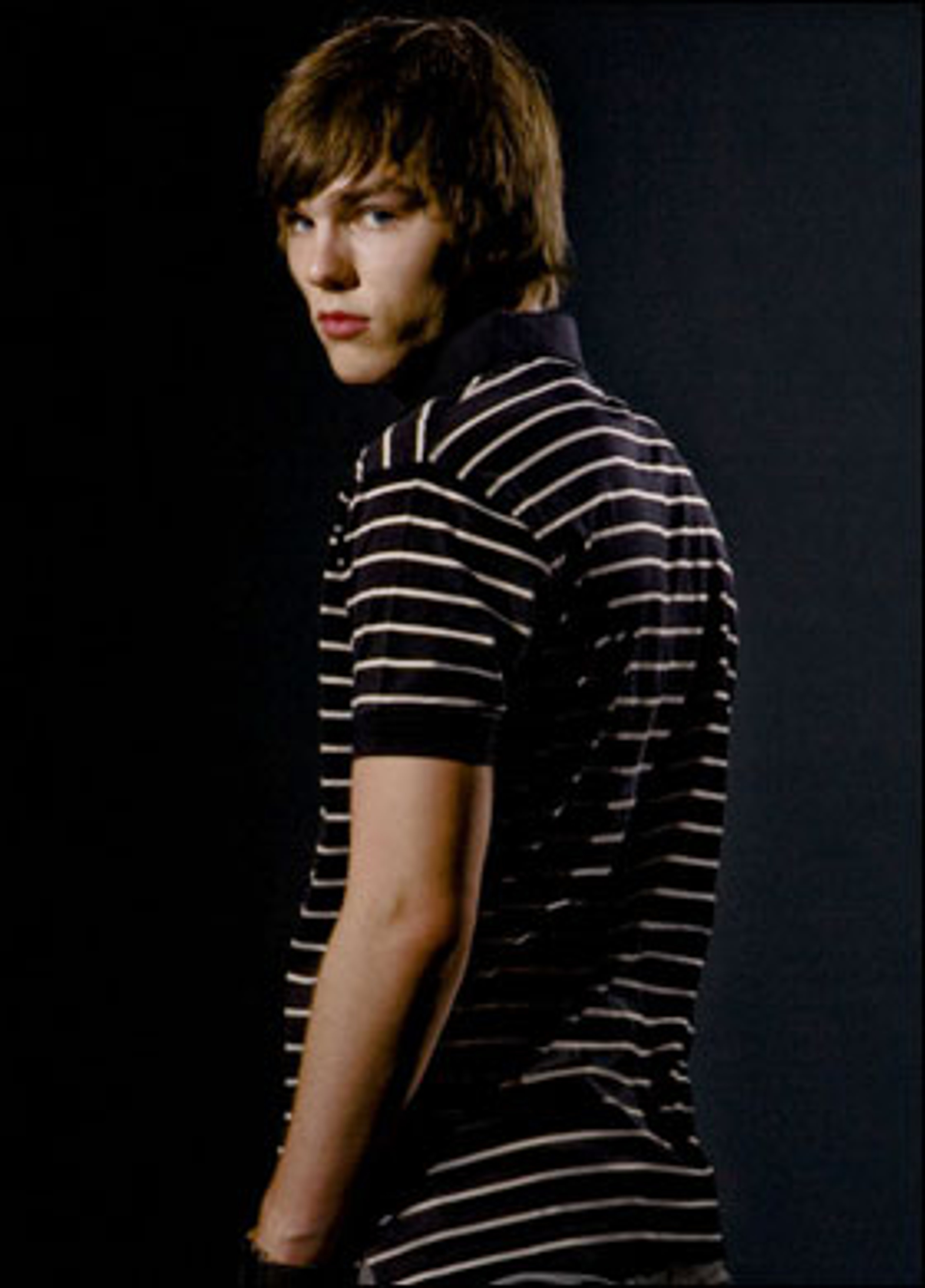 A young man with short brown hair wearing a striped shirt