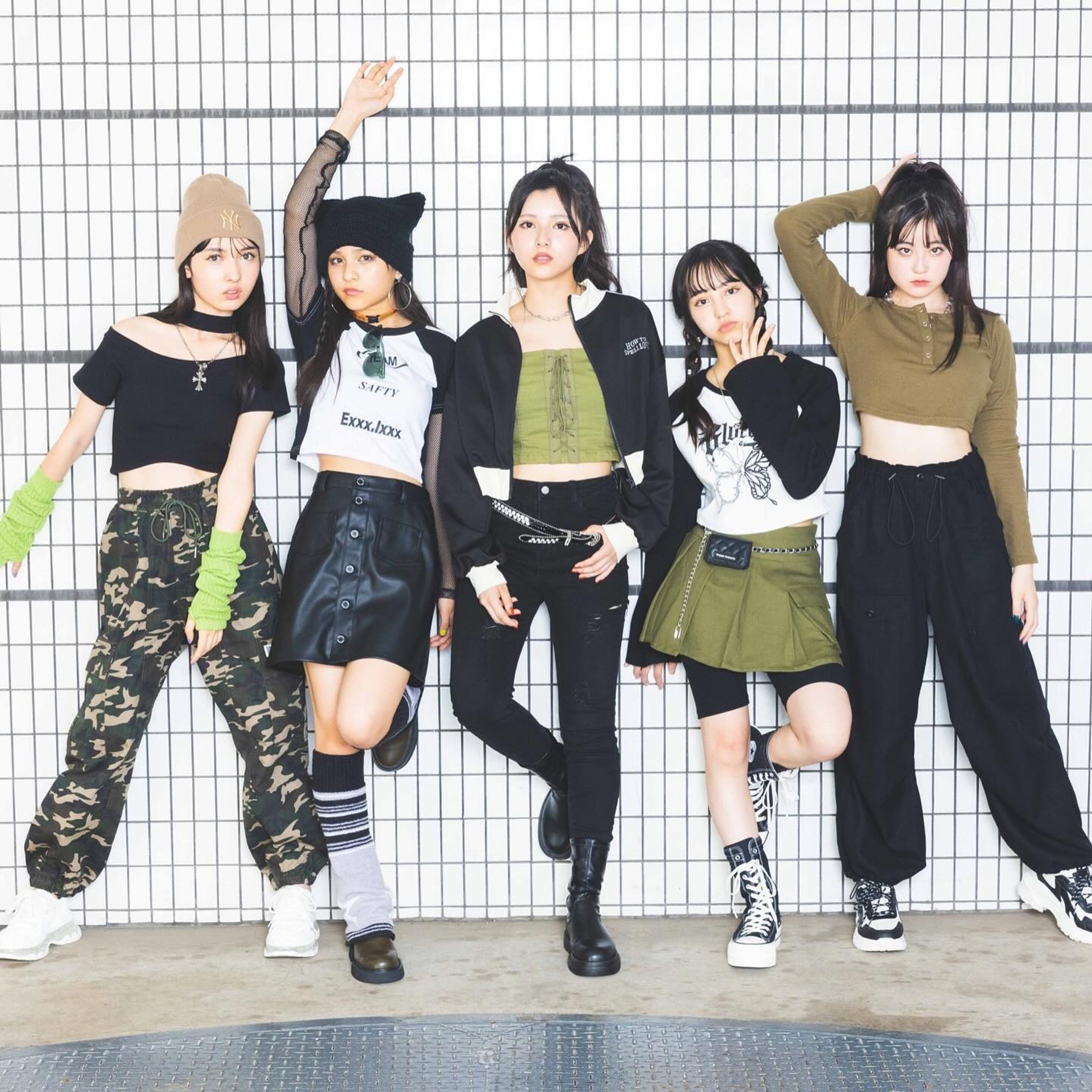 A group of five young women with dyed hair and edgy, cyberpunk-inspired fashion posing together in an urban setting.