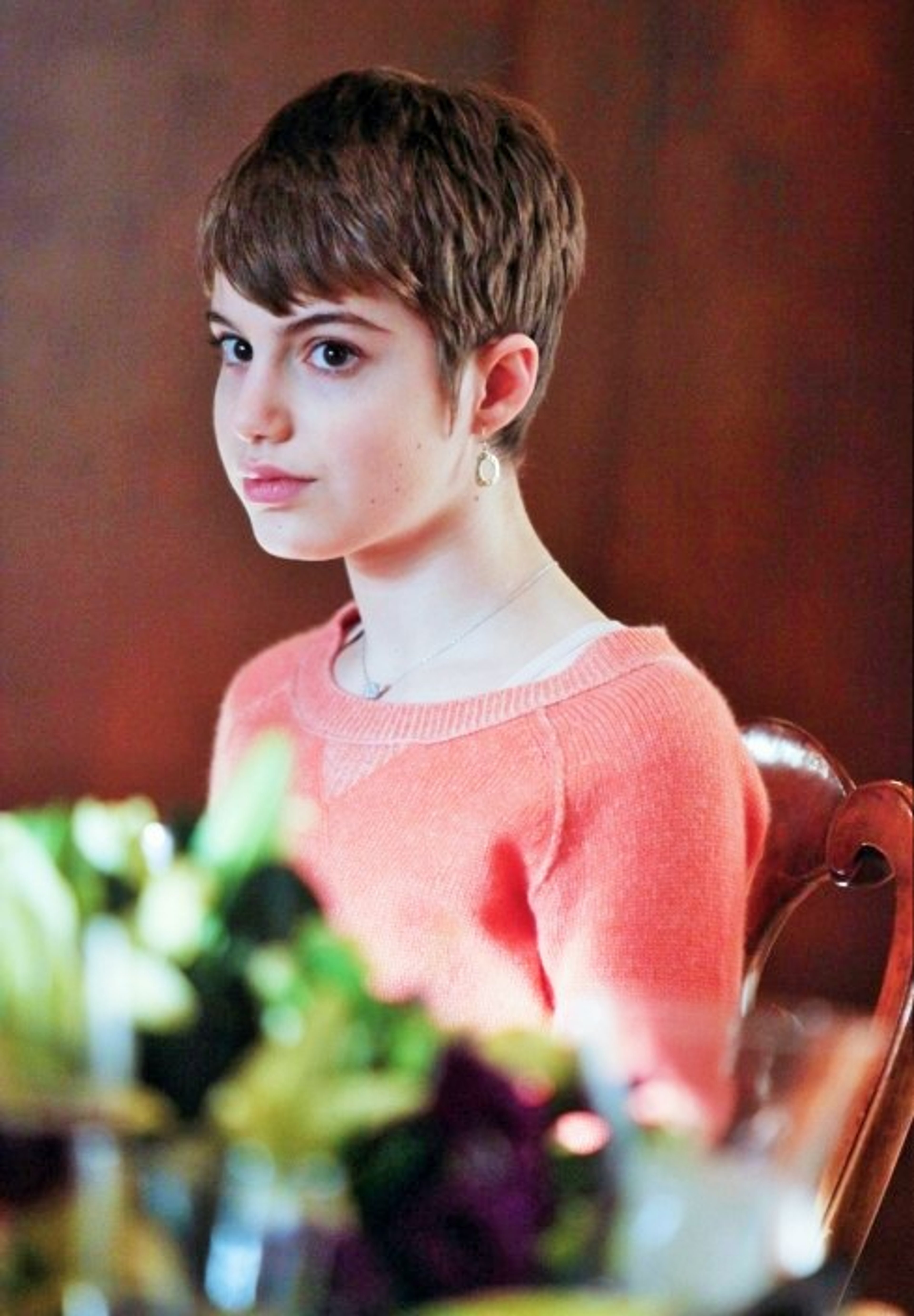 A young woman with short brown hair wearing a pink sweater