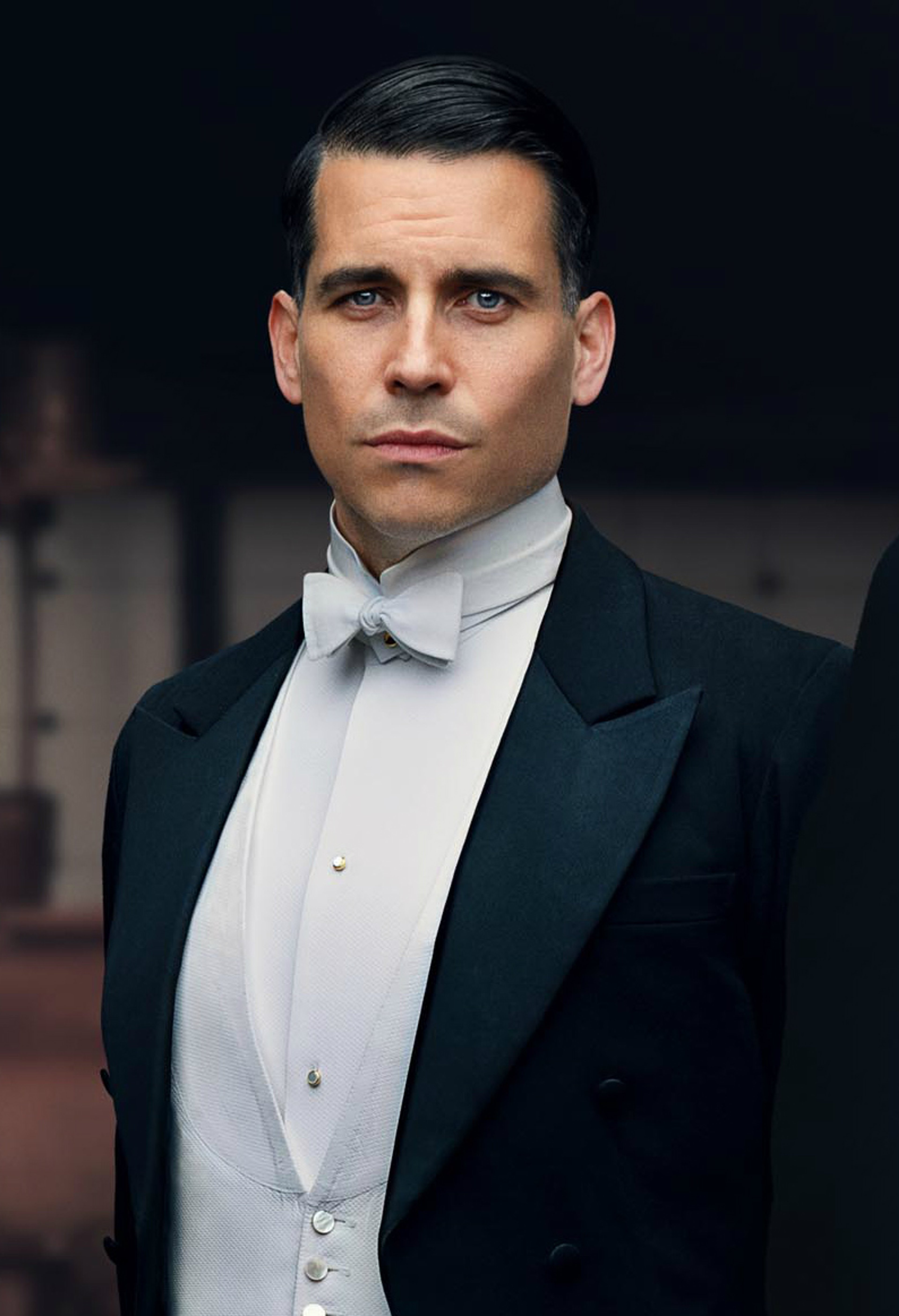 A man in a tuxedo with a serious expression