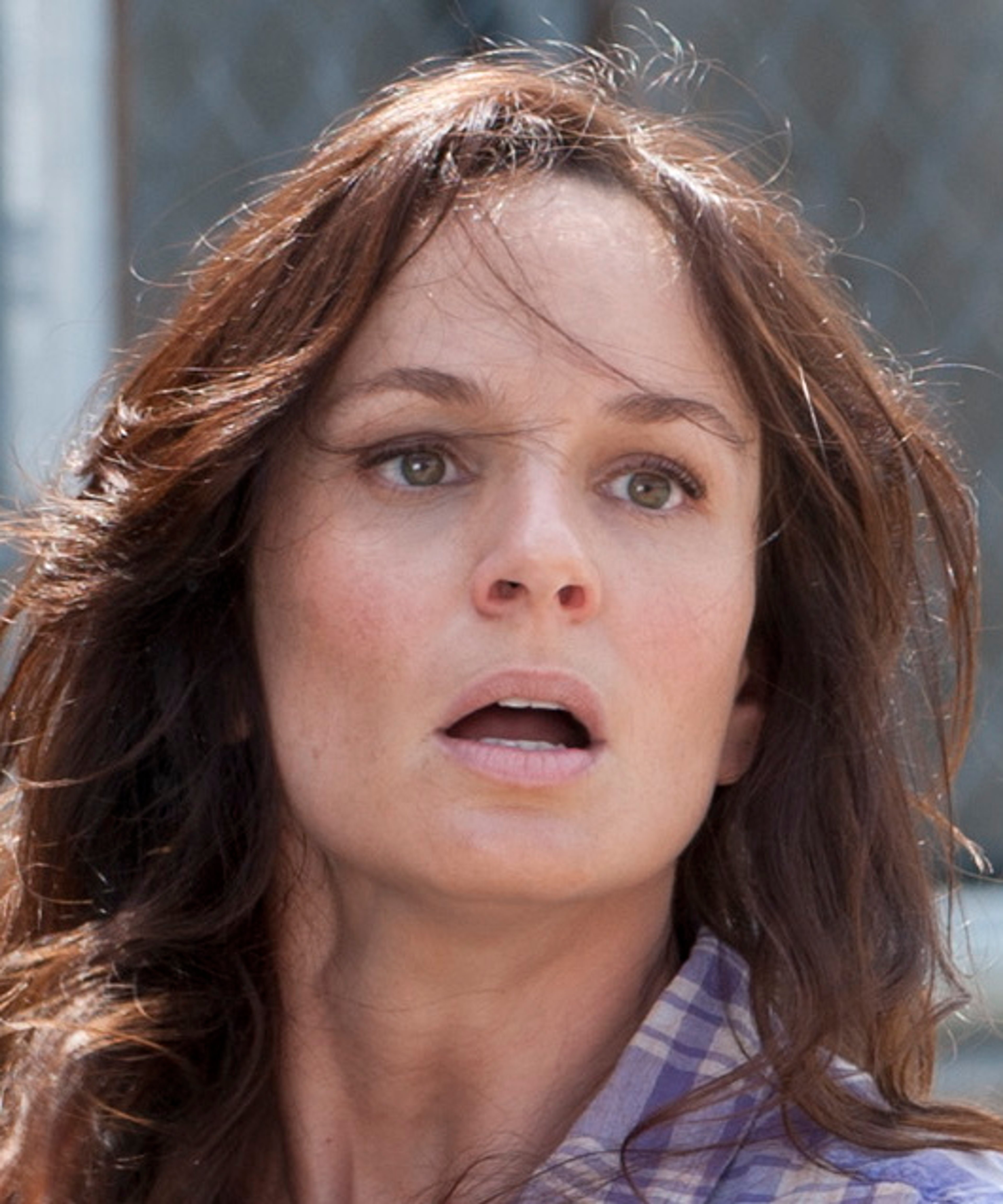 A woman with long brown hair and a concerned expression on her face