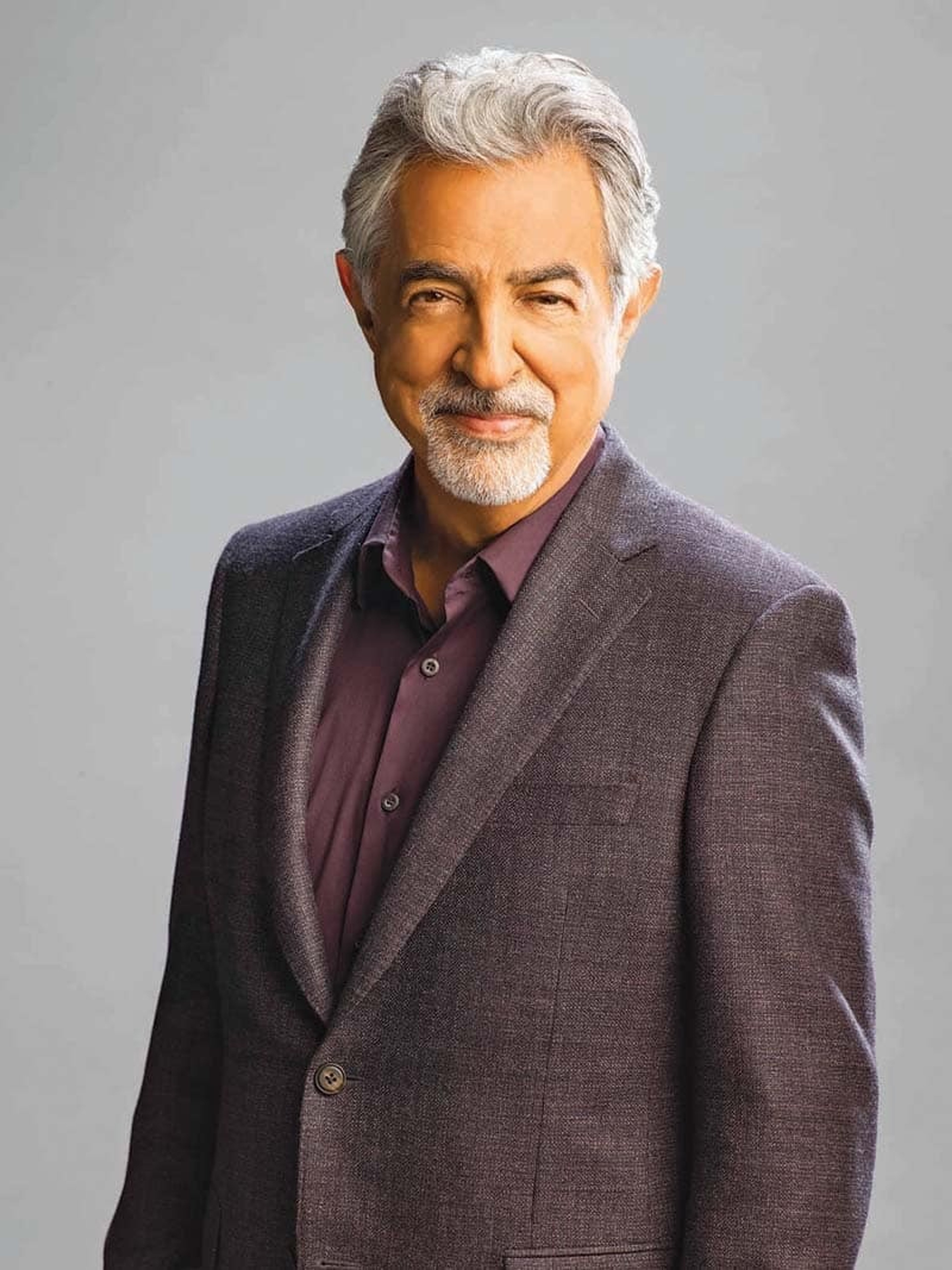 An older man with gray hair wearing a suit jacket and button-down shirt