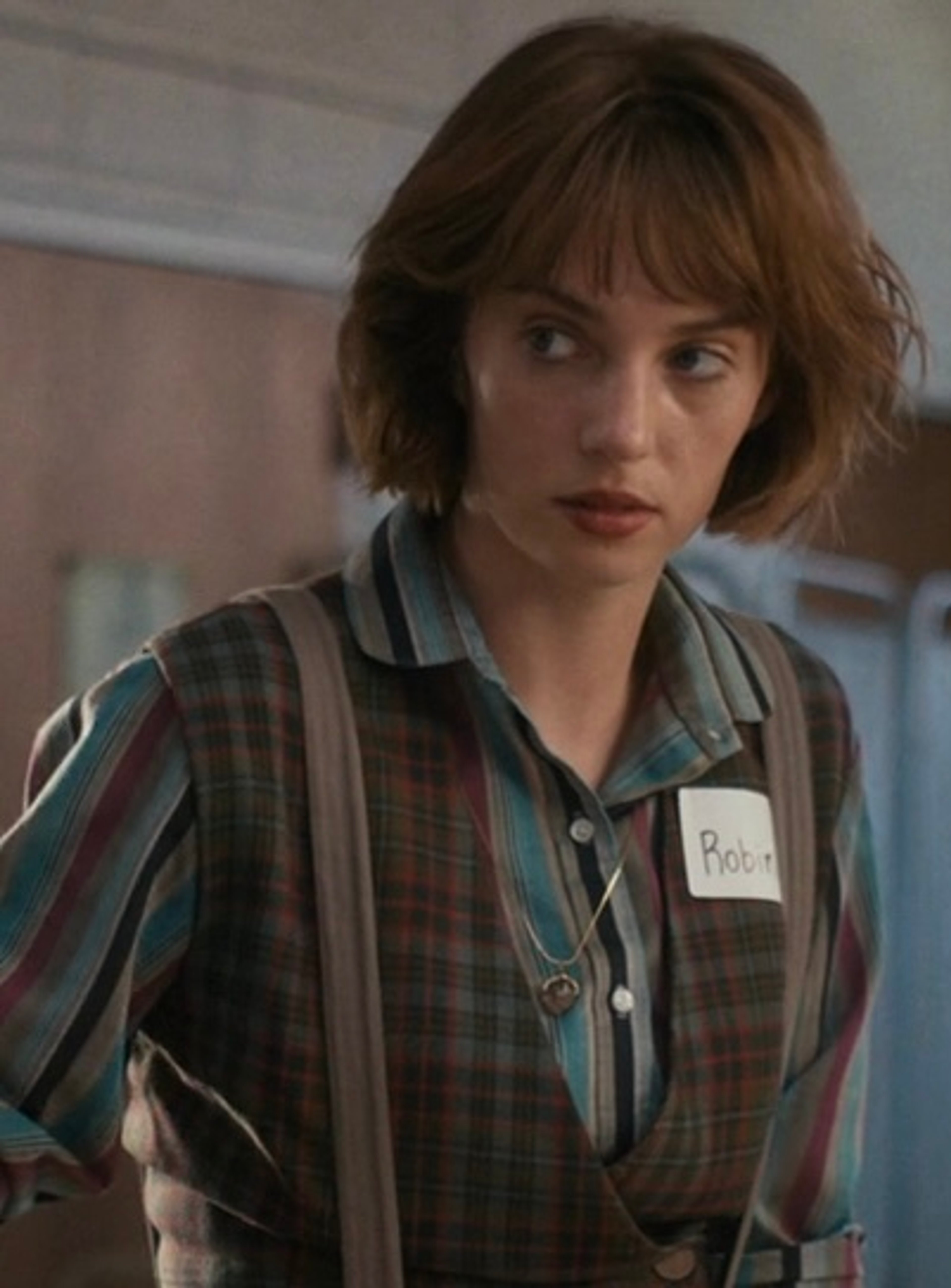 A young woman with short brown hair wearing a striped shirt and working at an ice cream shop