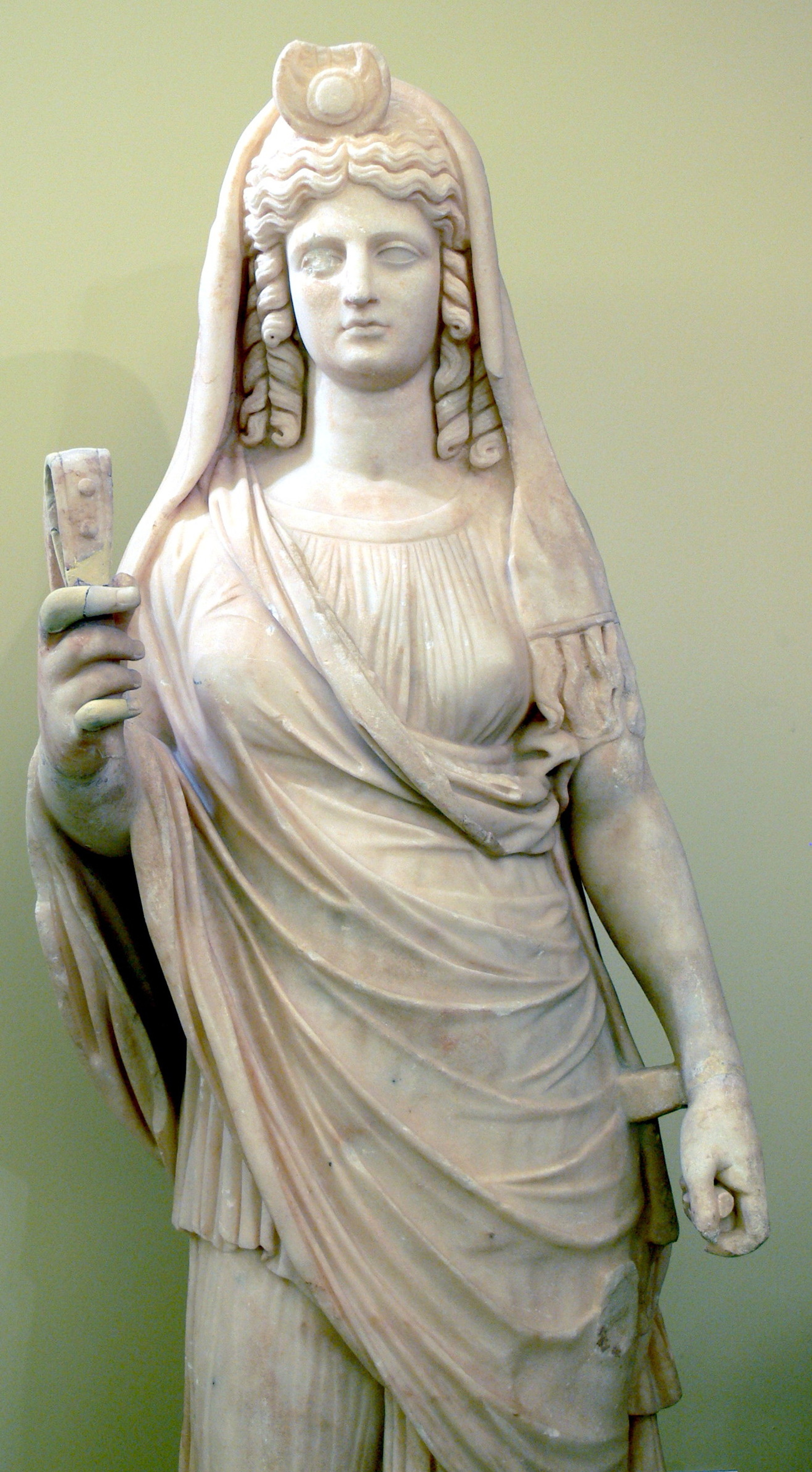 A detailed statue of a woman in flowing robes and an elaborate headdress, holding a pomegranate.