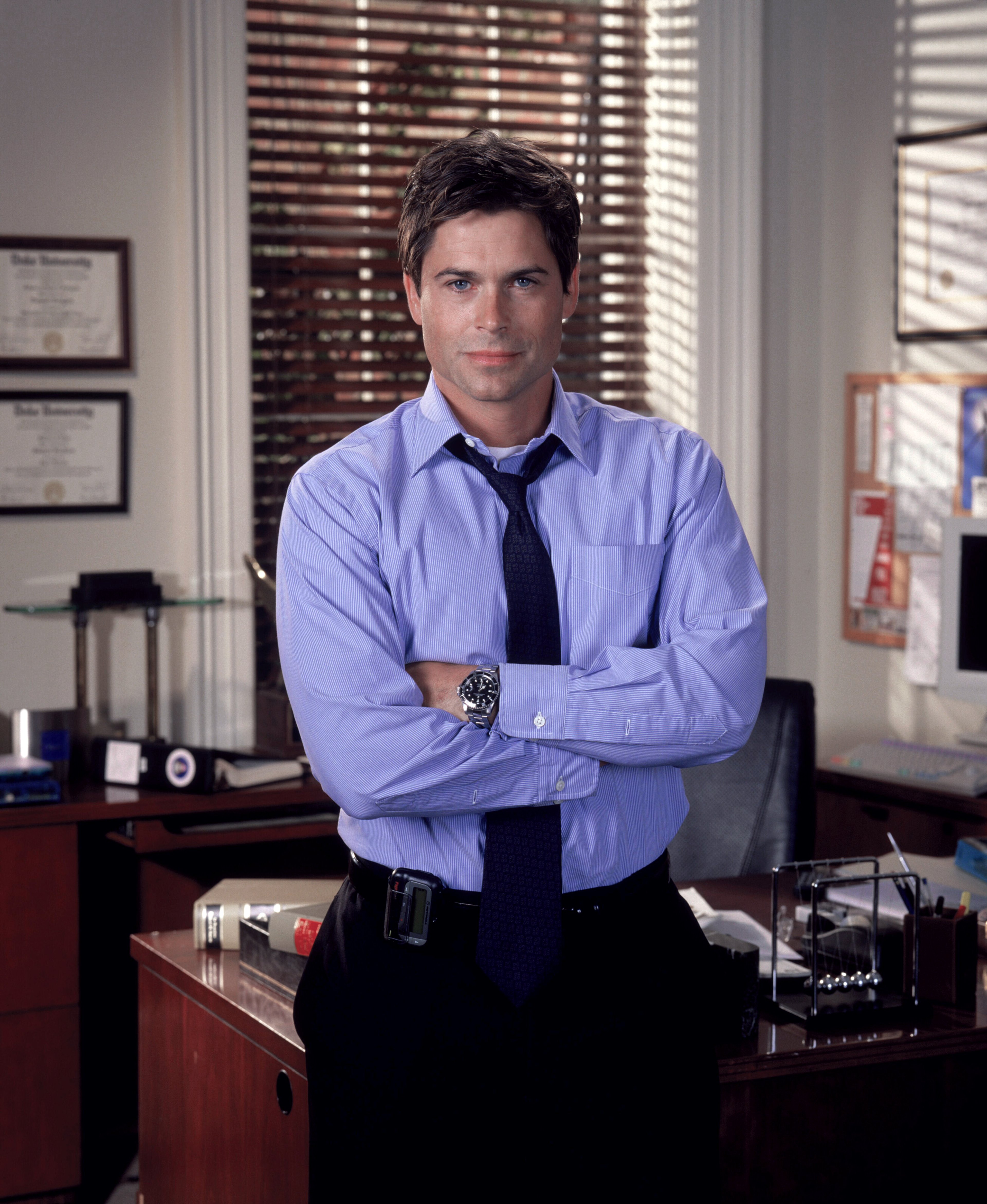 A man in a blue shirt and tie standing in an office