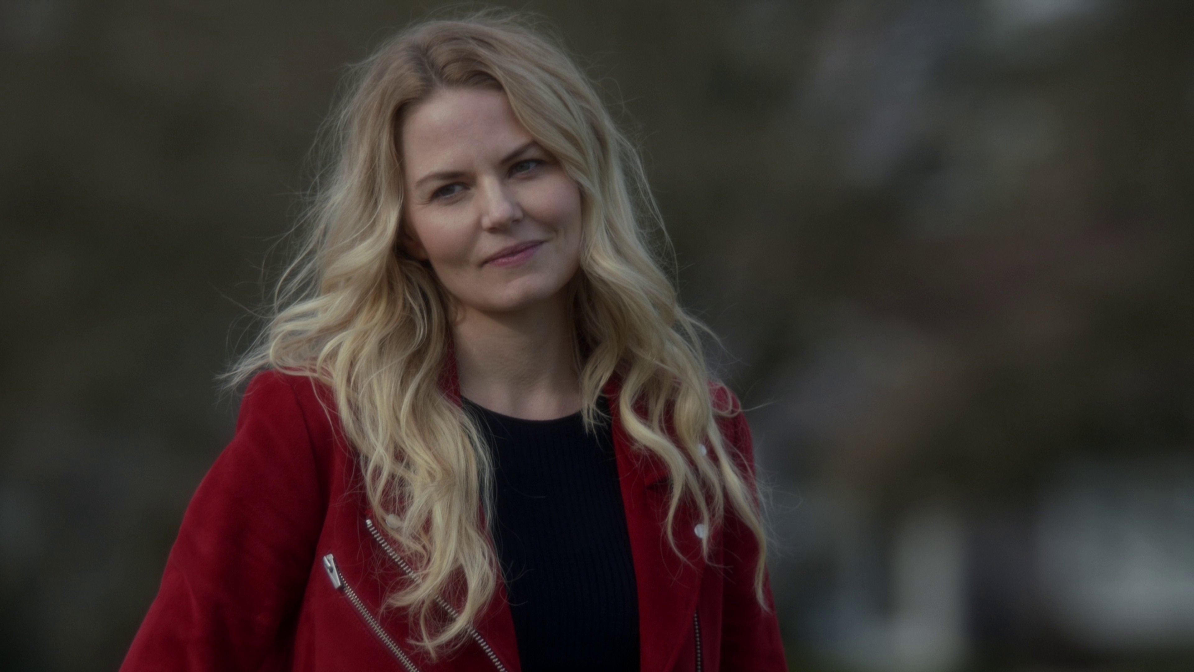 A woman with long blonde hair wearing a red jacket in an outdoor setting