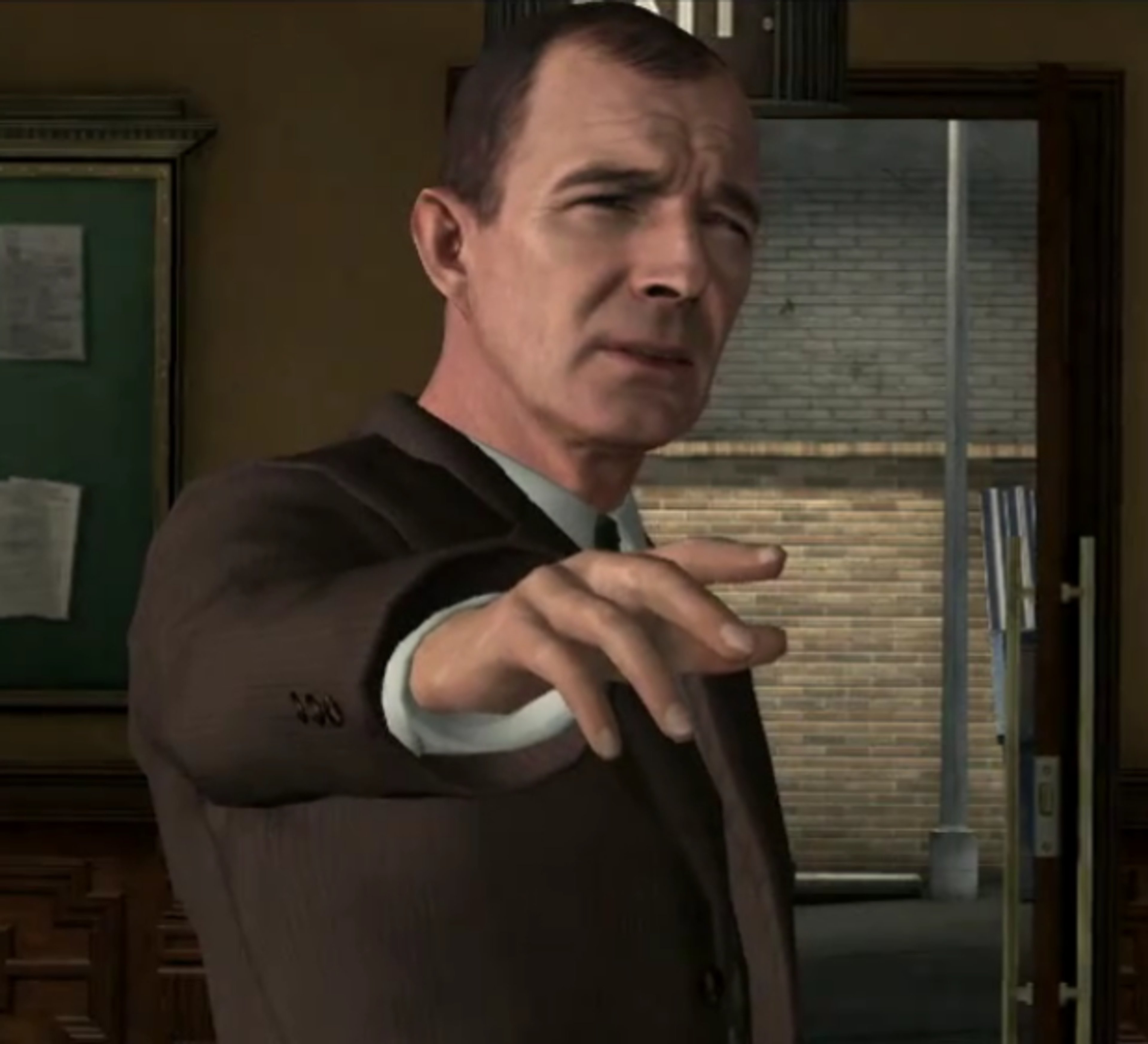 A middle-aged man in a suit and tie, with a stern expression, standing in an office setting.