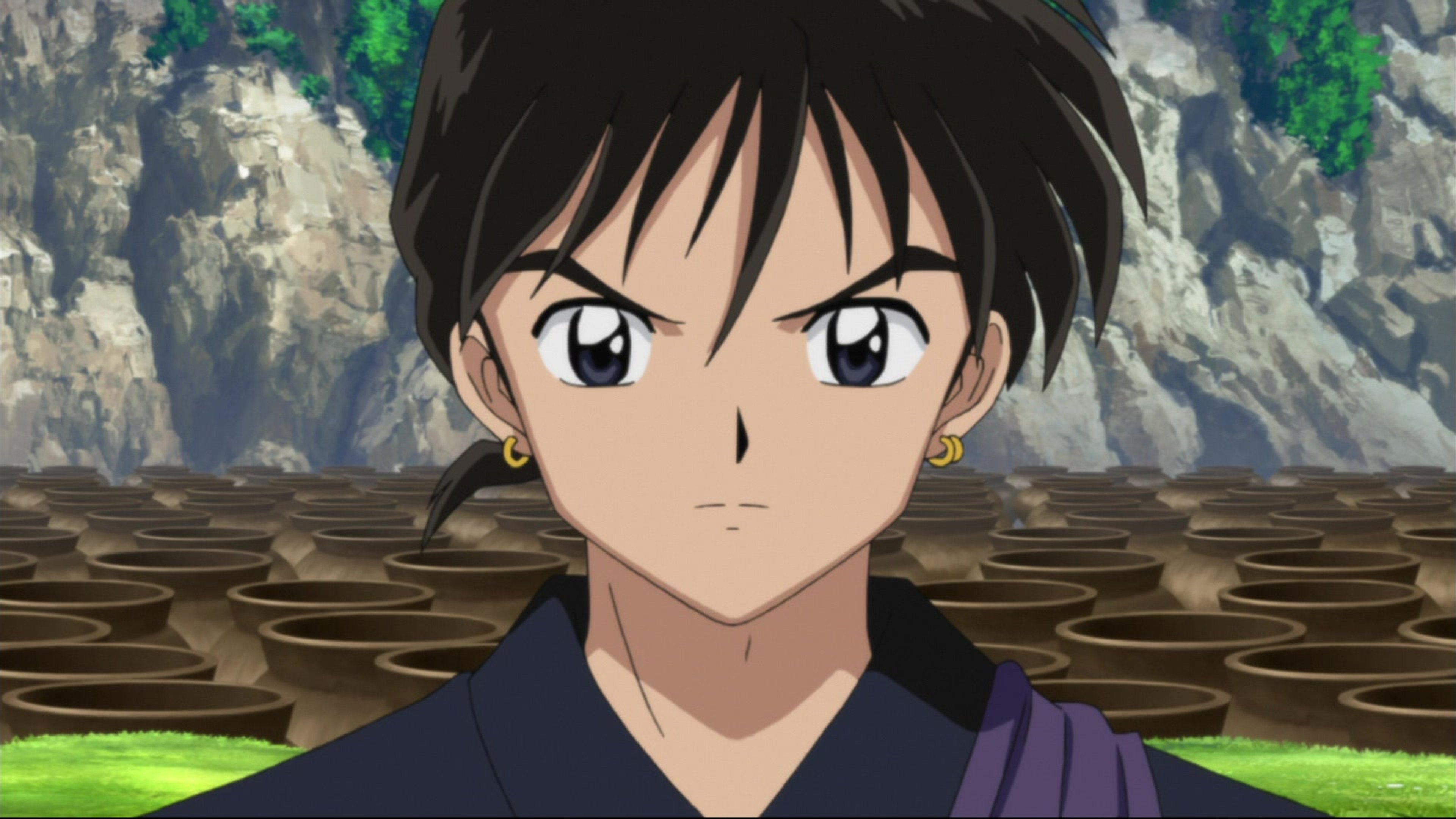 An anime-style character of a Buddhist monk with short dark hair, wearing a purple robe and holding a staff.