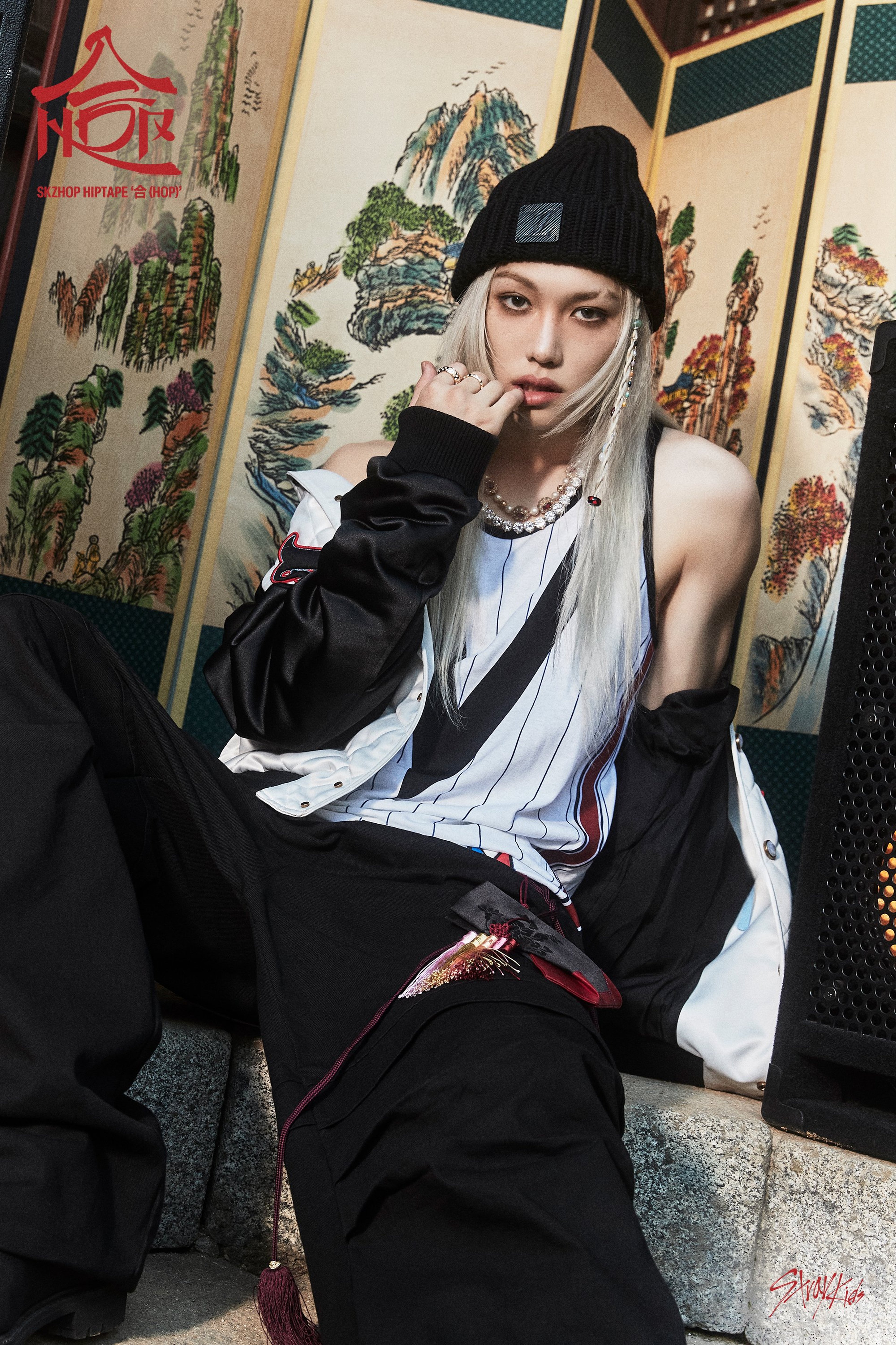 A young woman with light hair wearing a black outfit in a traditional Asian-style setting