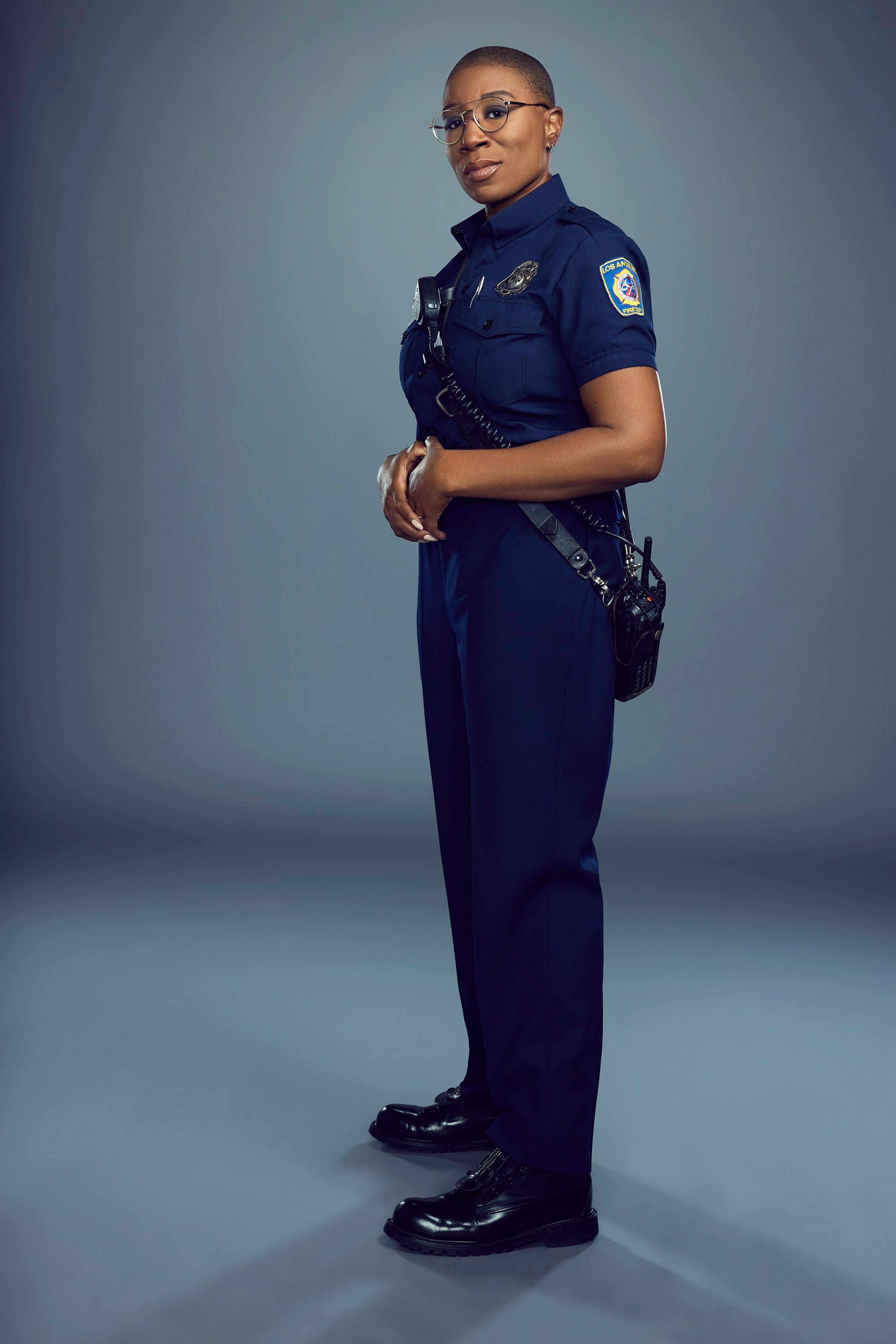A Black woman in a firefighter's uniform standing with a serious expression