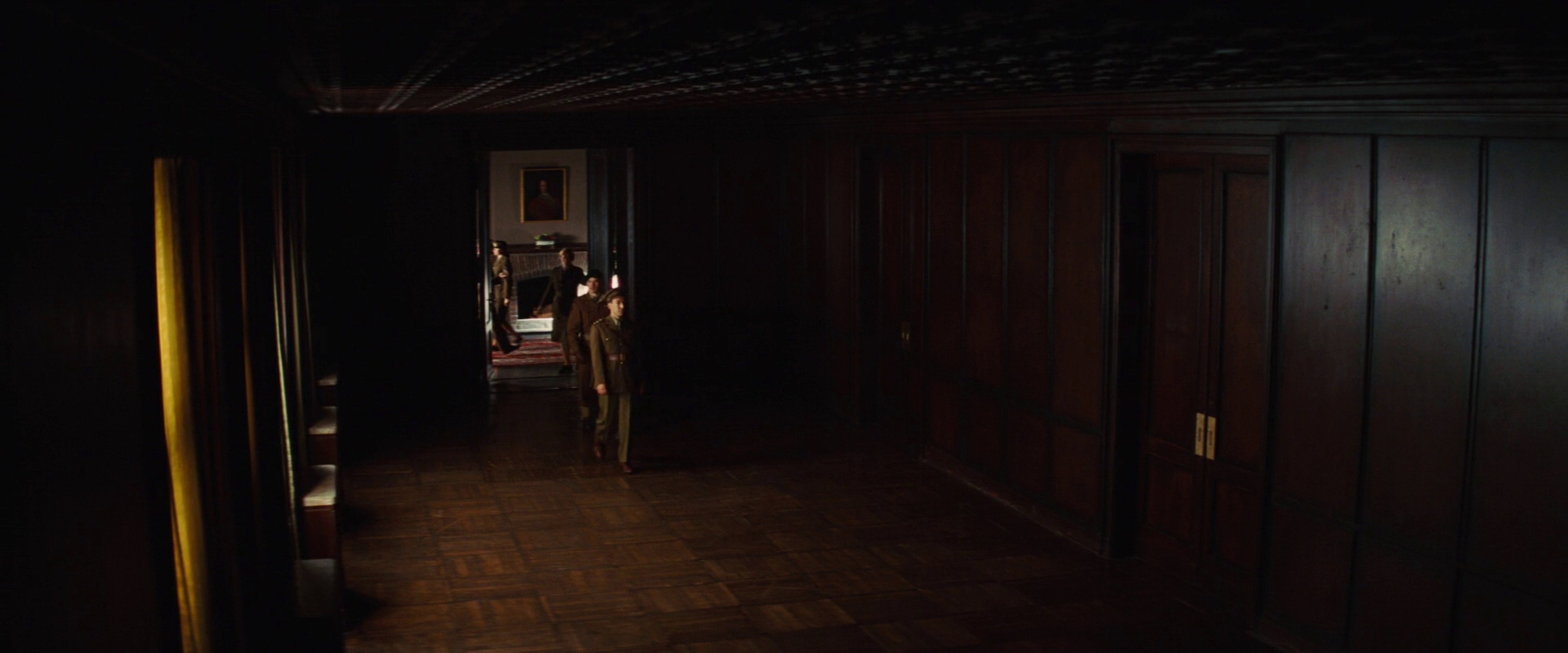A dark, moody hallway with wooden paneled walls and a single light fixture.