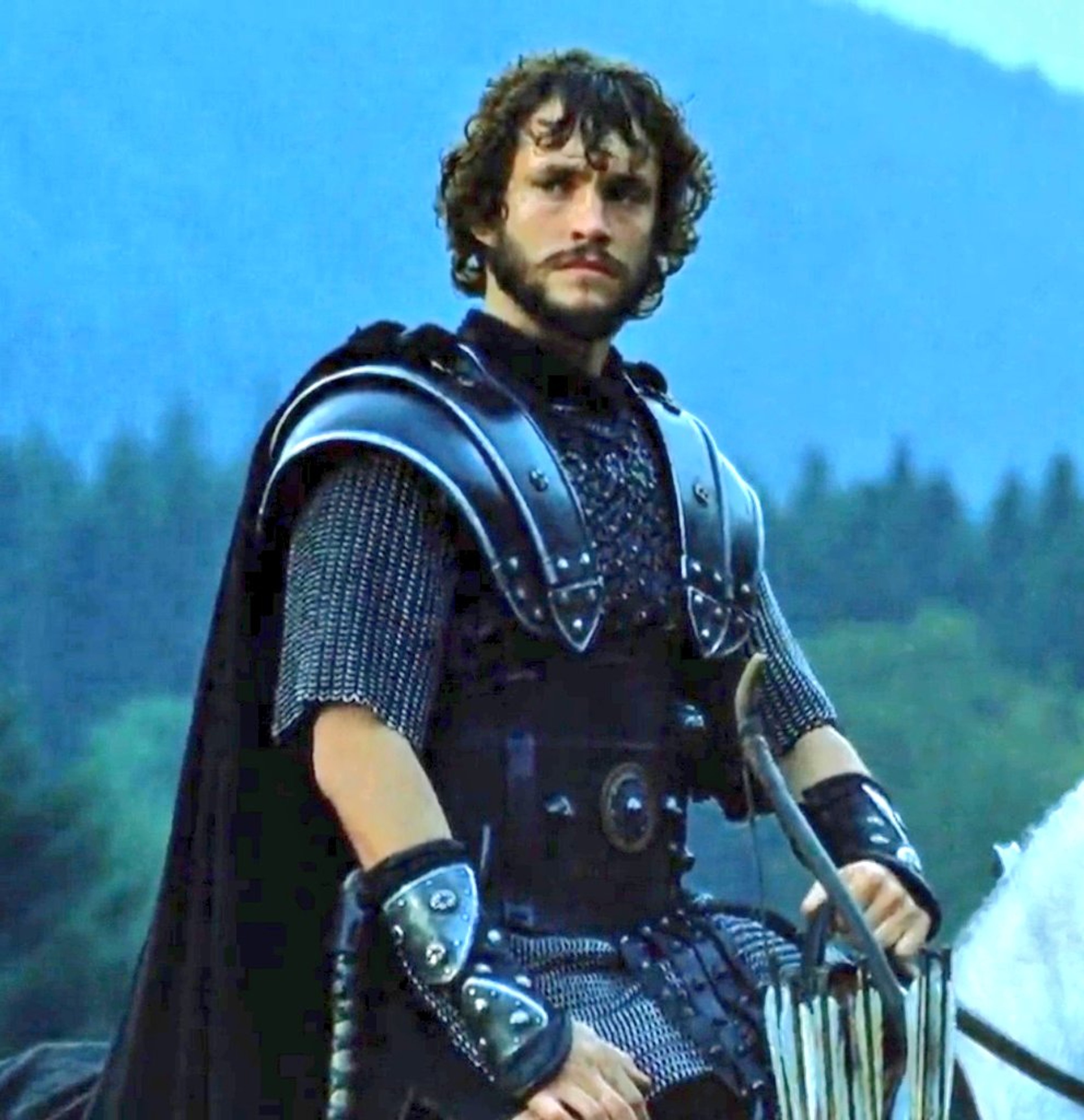 A young medieval knight or soldier standing in a natural outdoor setting