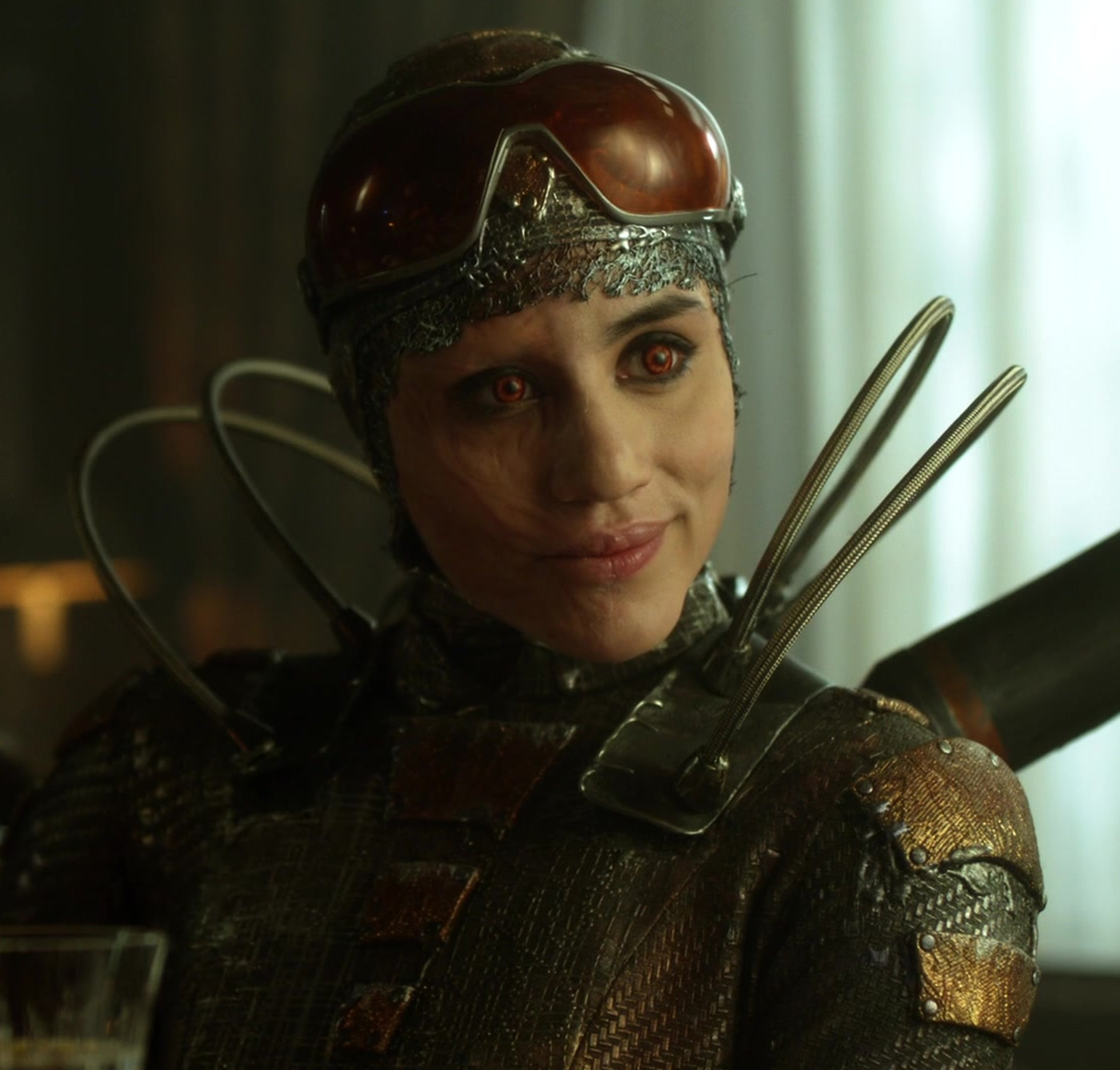 A woman in a dark, armored supervillain costume with glowing red eyes