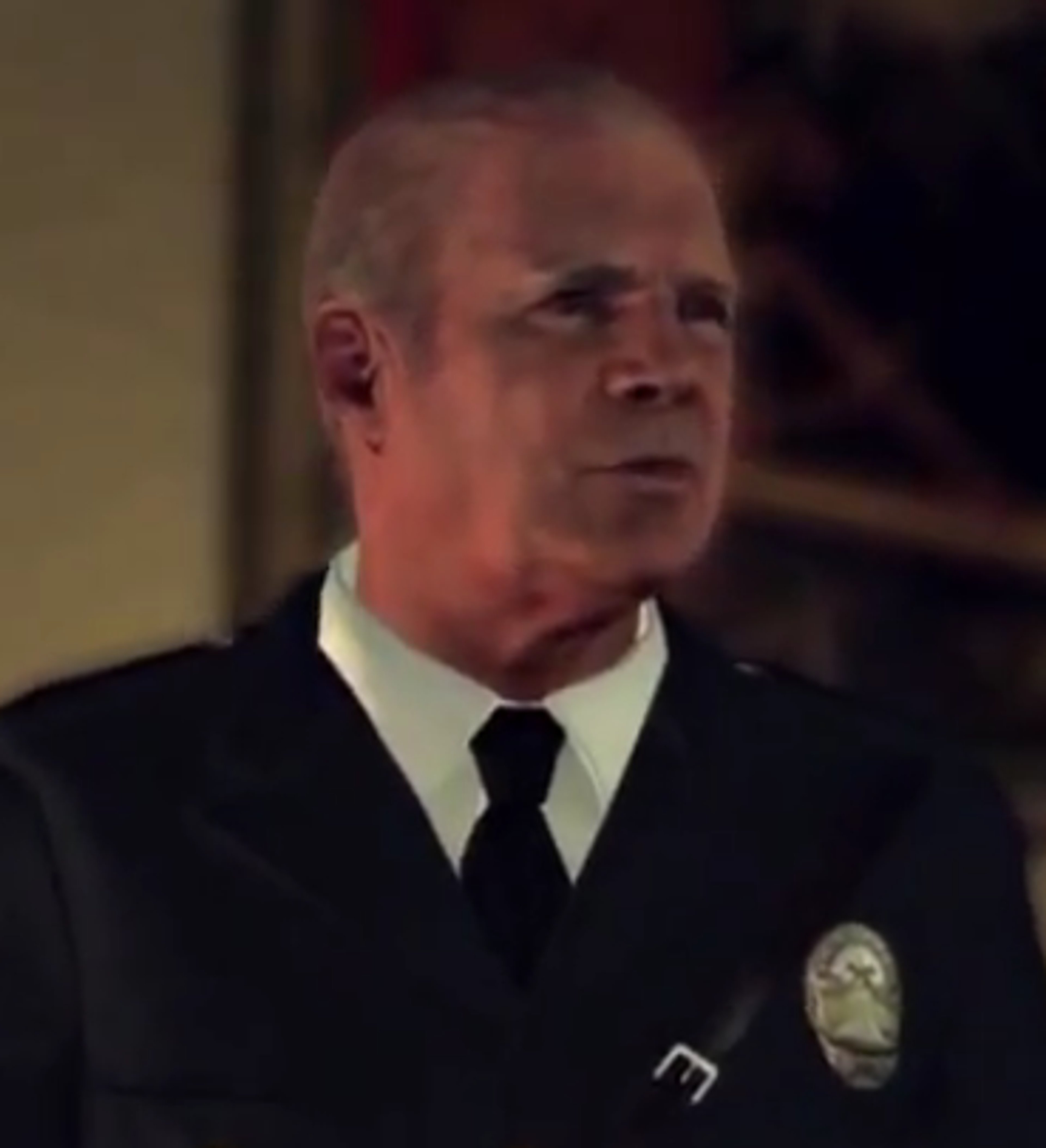 A man in a police uniform with a stern expression