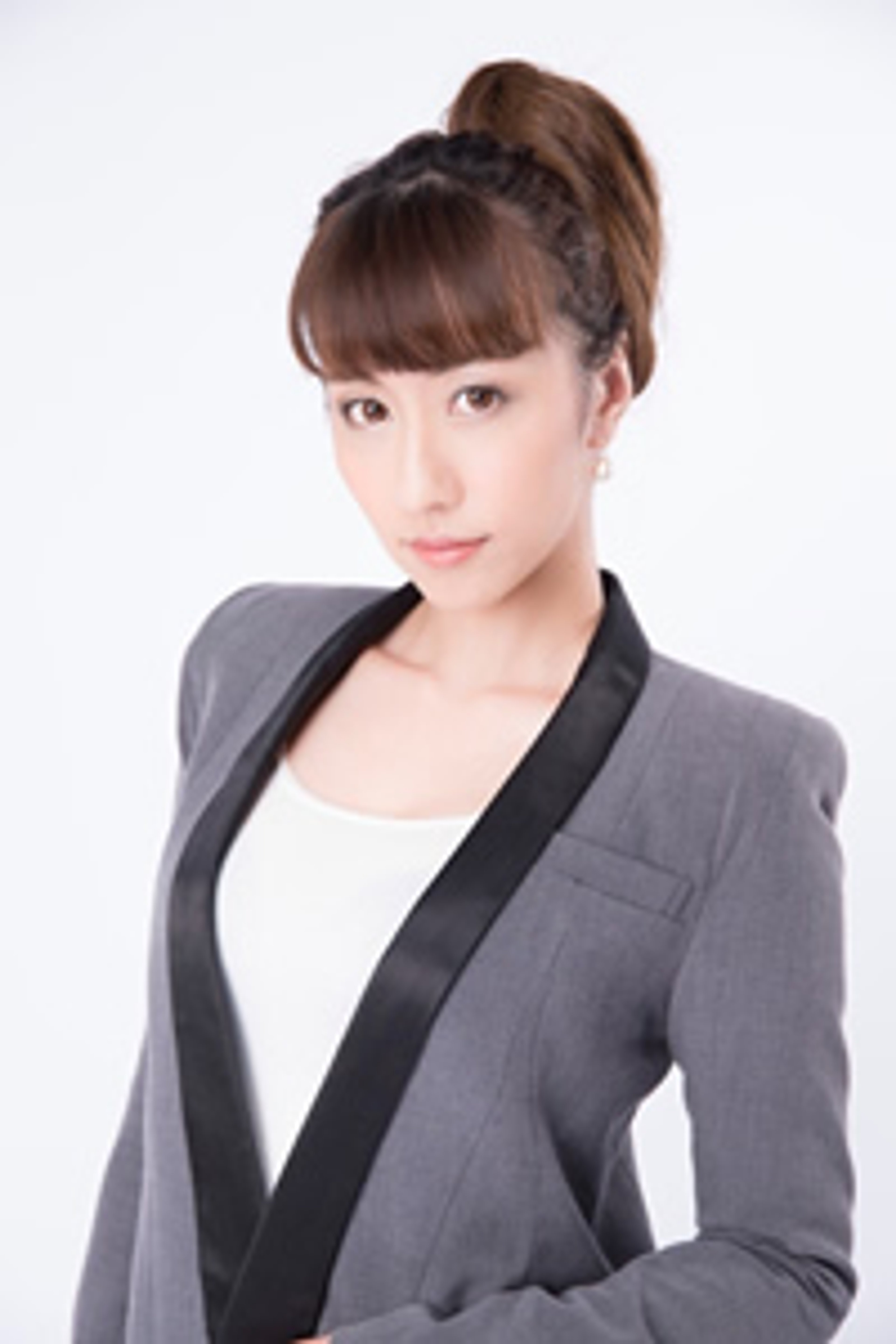A young woman with long brown hair in a ponytail, wearing a gray blazer and looking directly at the camera.