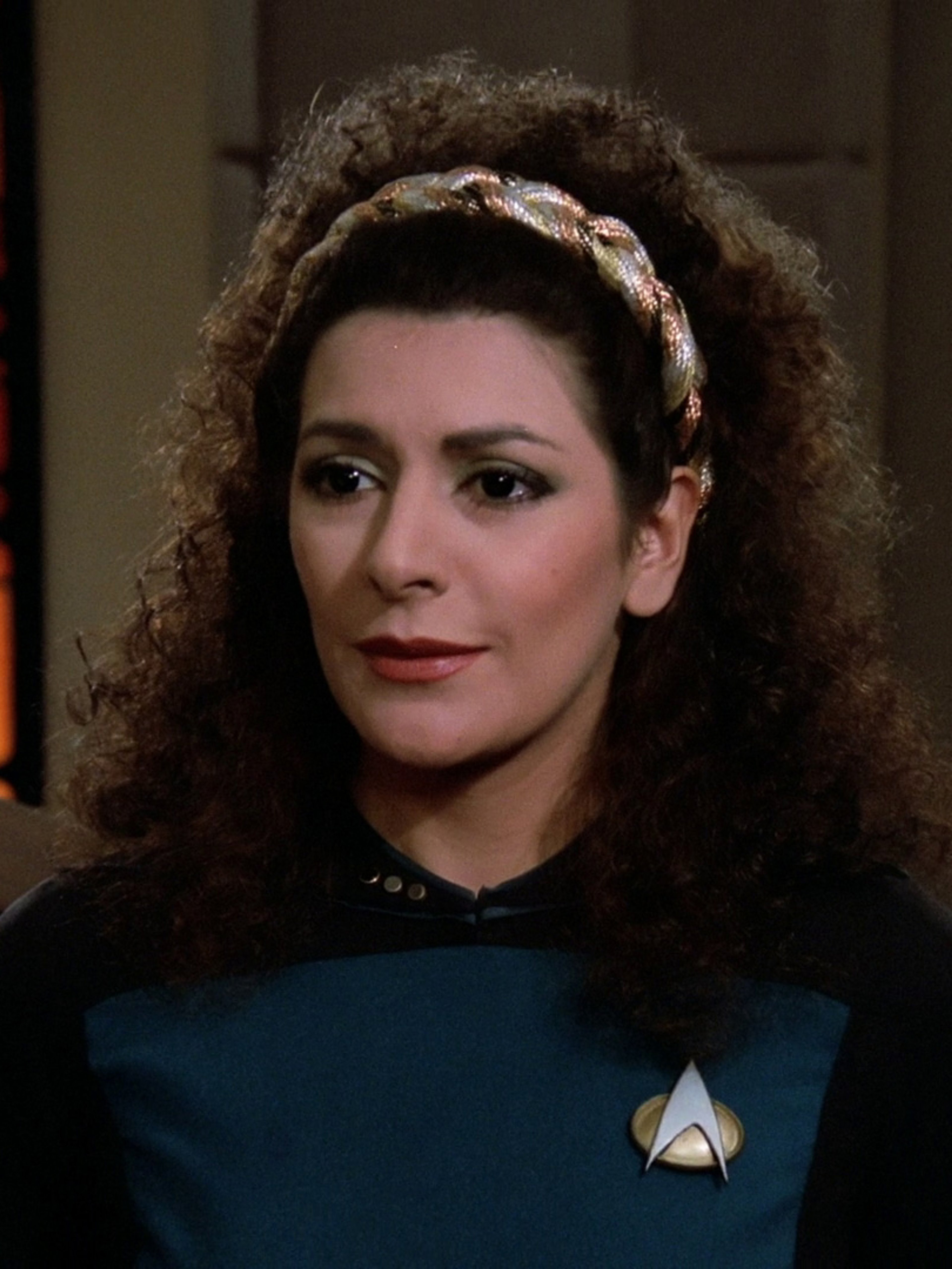 A woman in a Starfleet uniform with curly dark hair