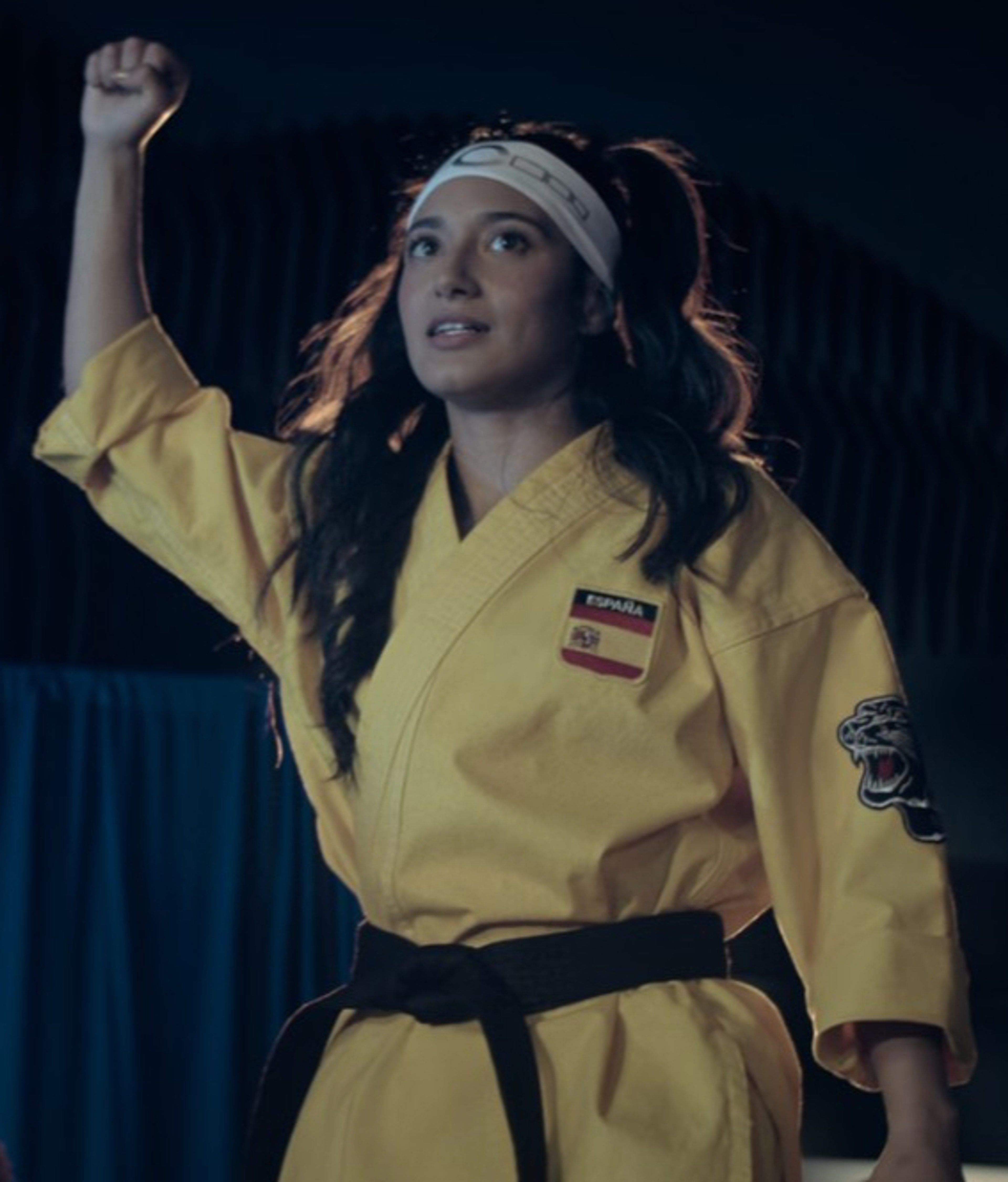 A young woman in a yellow karate uniform in a fighting stance