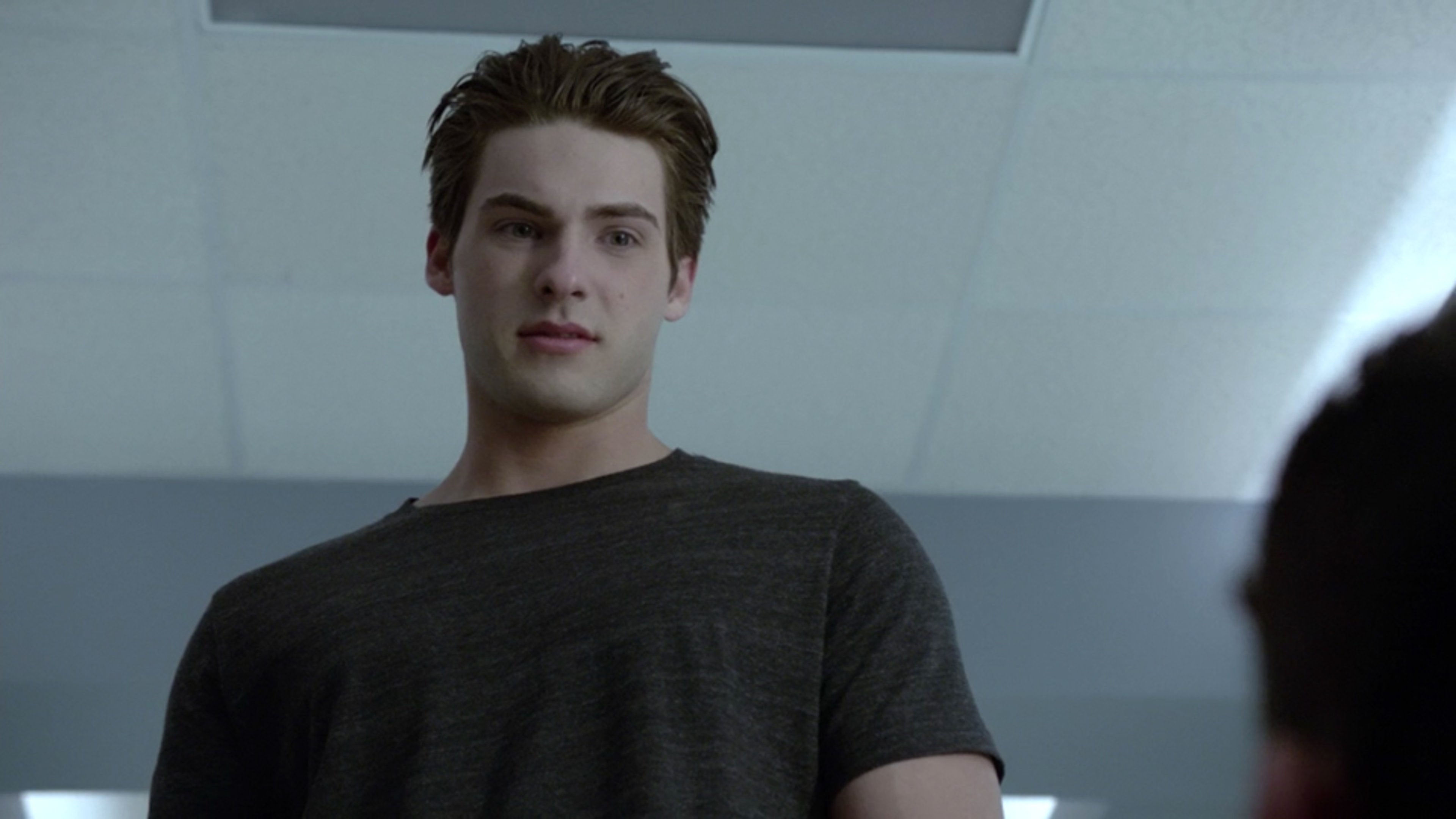 A young man with short brown hair and a serious expression