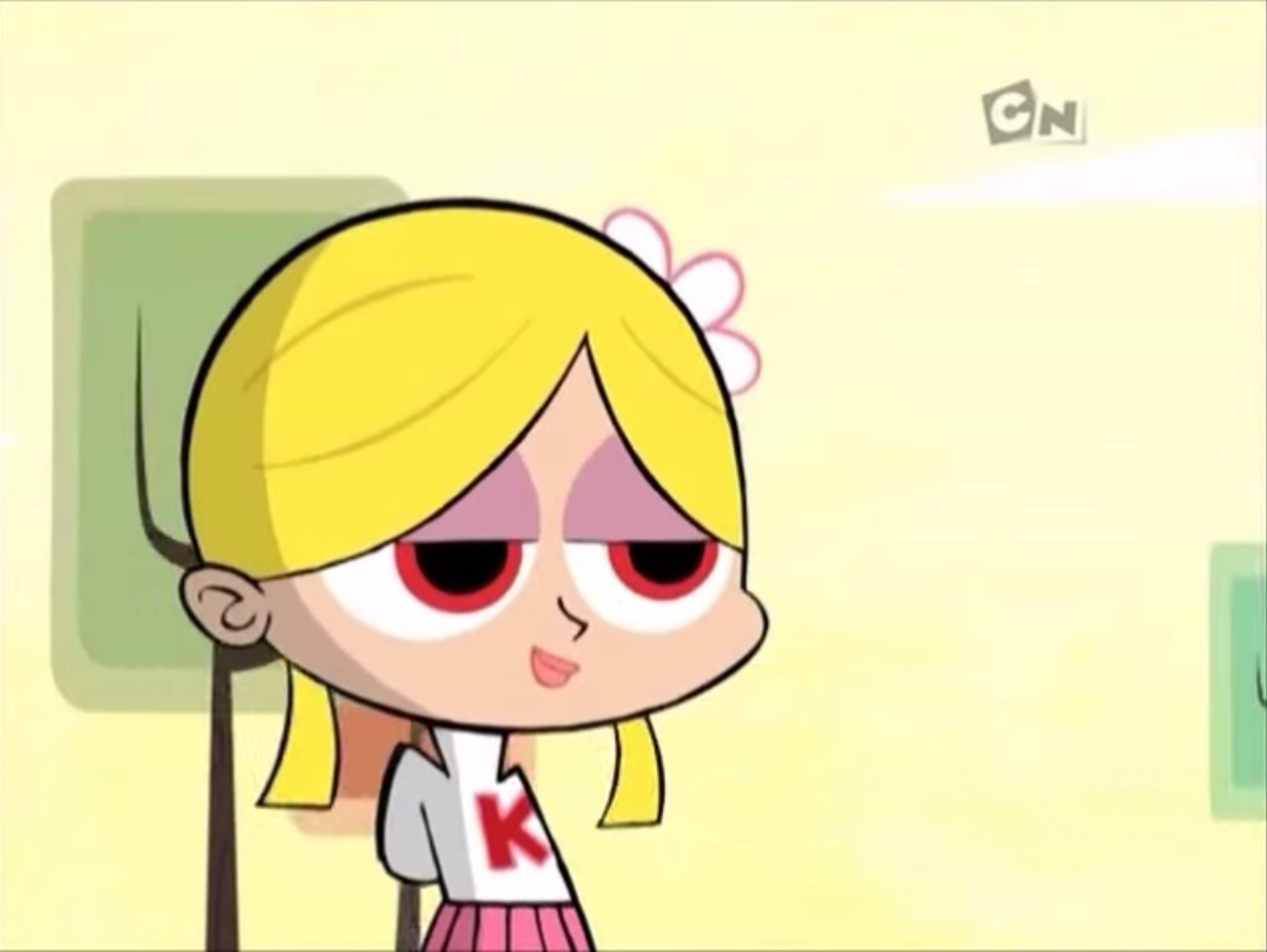 An anime-style character with blonde pigtails and red eyes wearing a shirt with a 'K' symbol