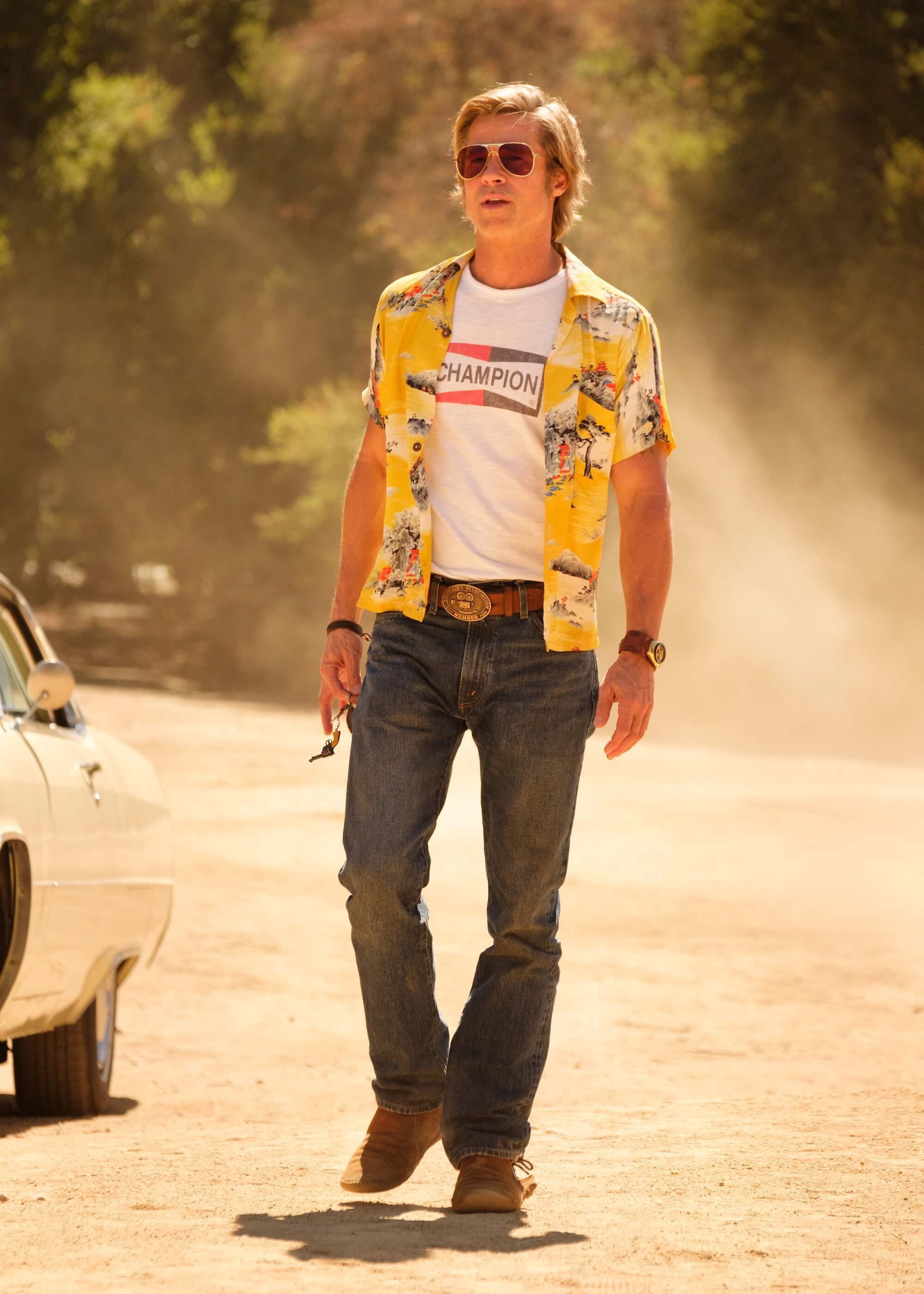 A man in a floral print shirt walking down a dirt road