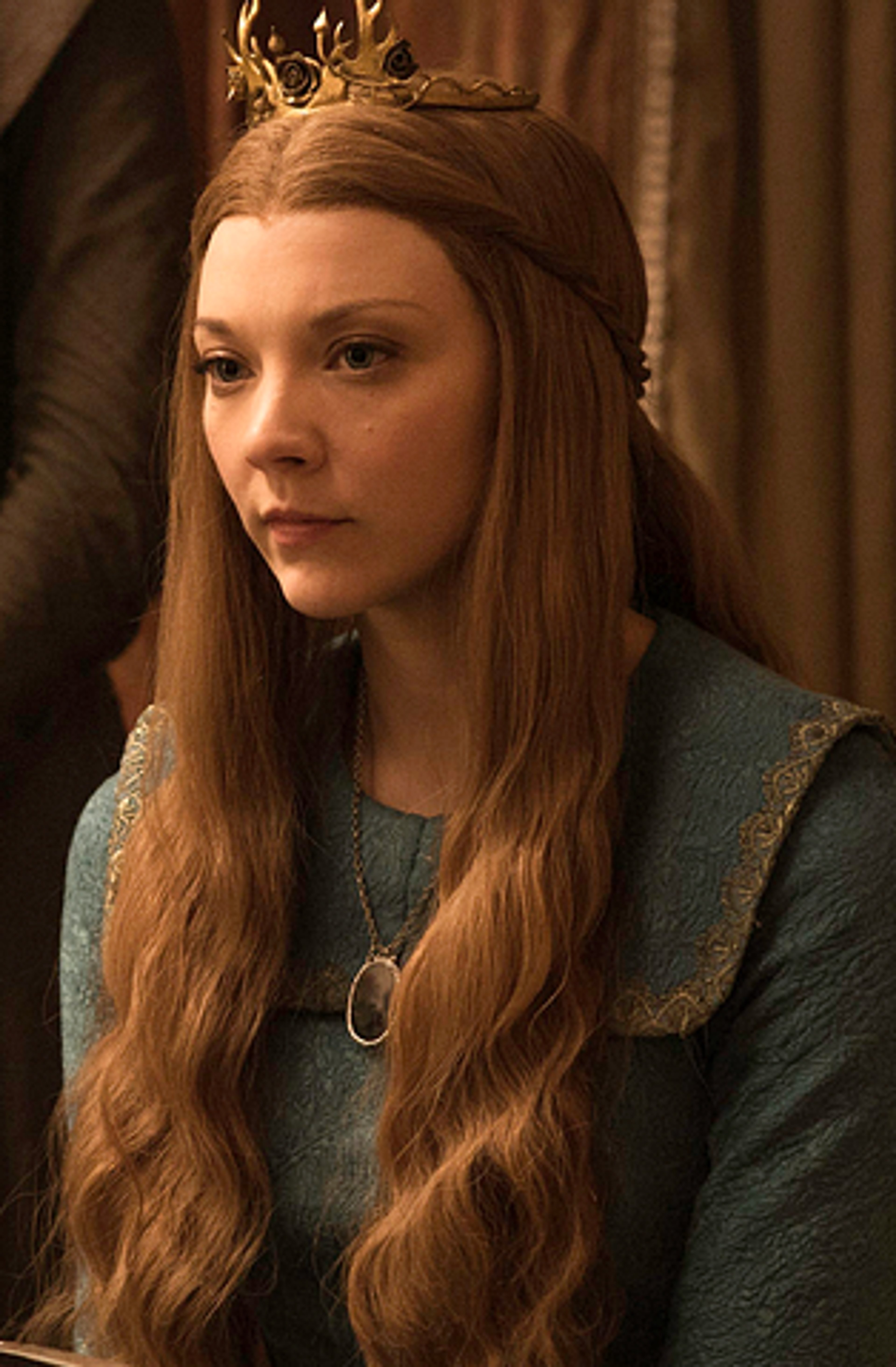 A young woman with long brown hair and a crown-like headpiece, wearing a green dress with intricate embroidery.