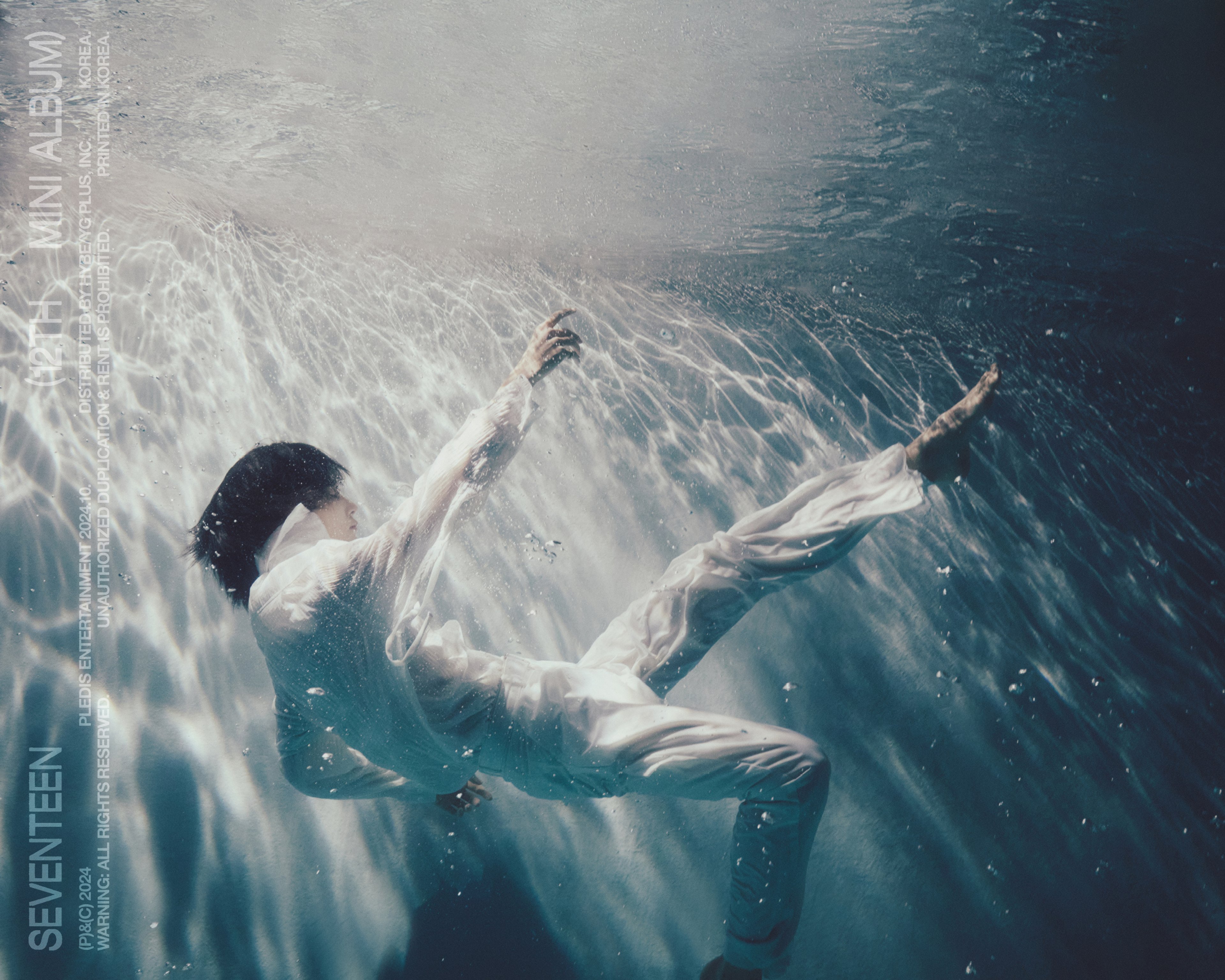 A person swimming underwater with their arms raised above their head.