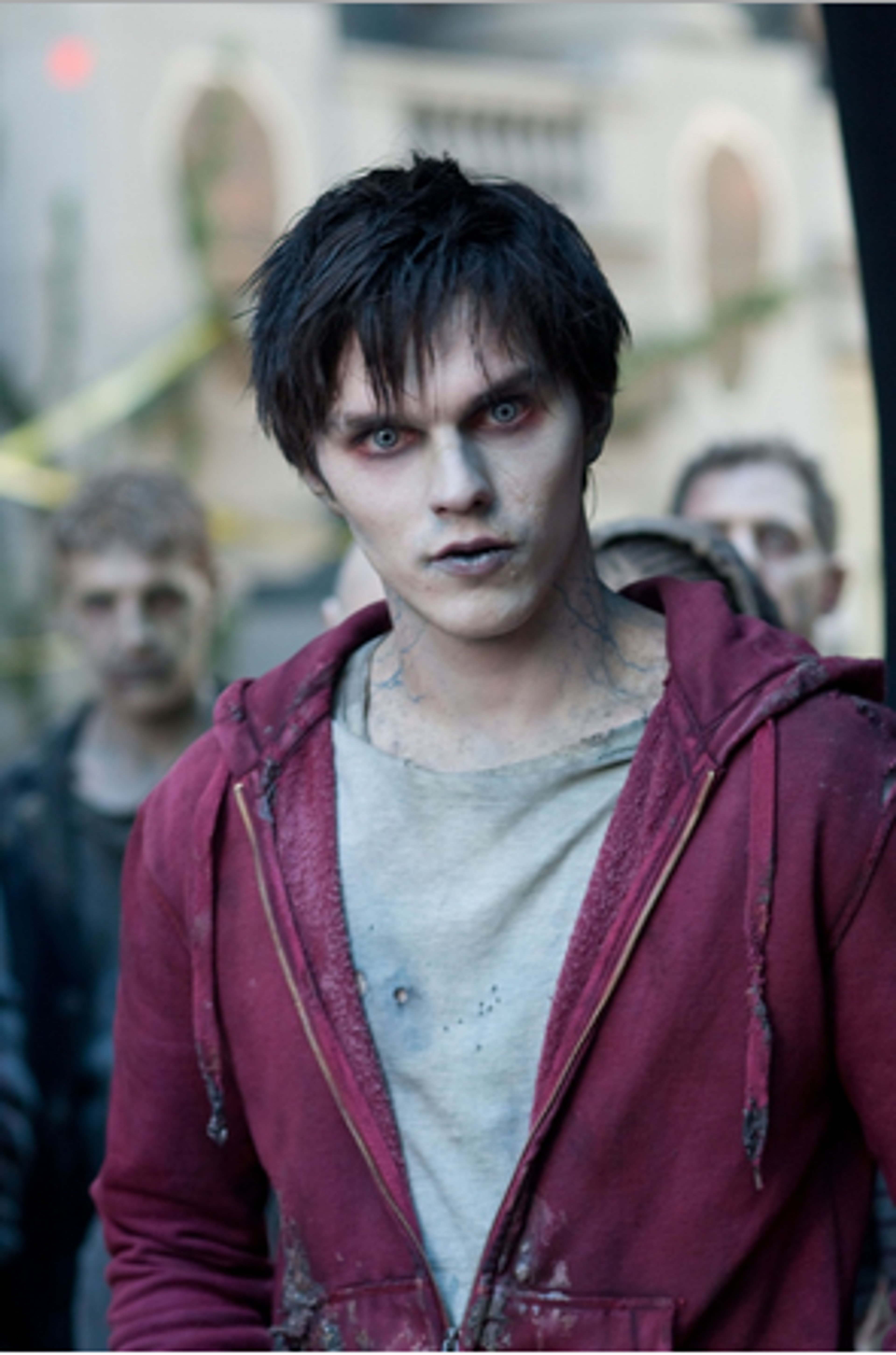 A young man with dark hair wearing a red hooded jacket in a post-apocalyptic setting