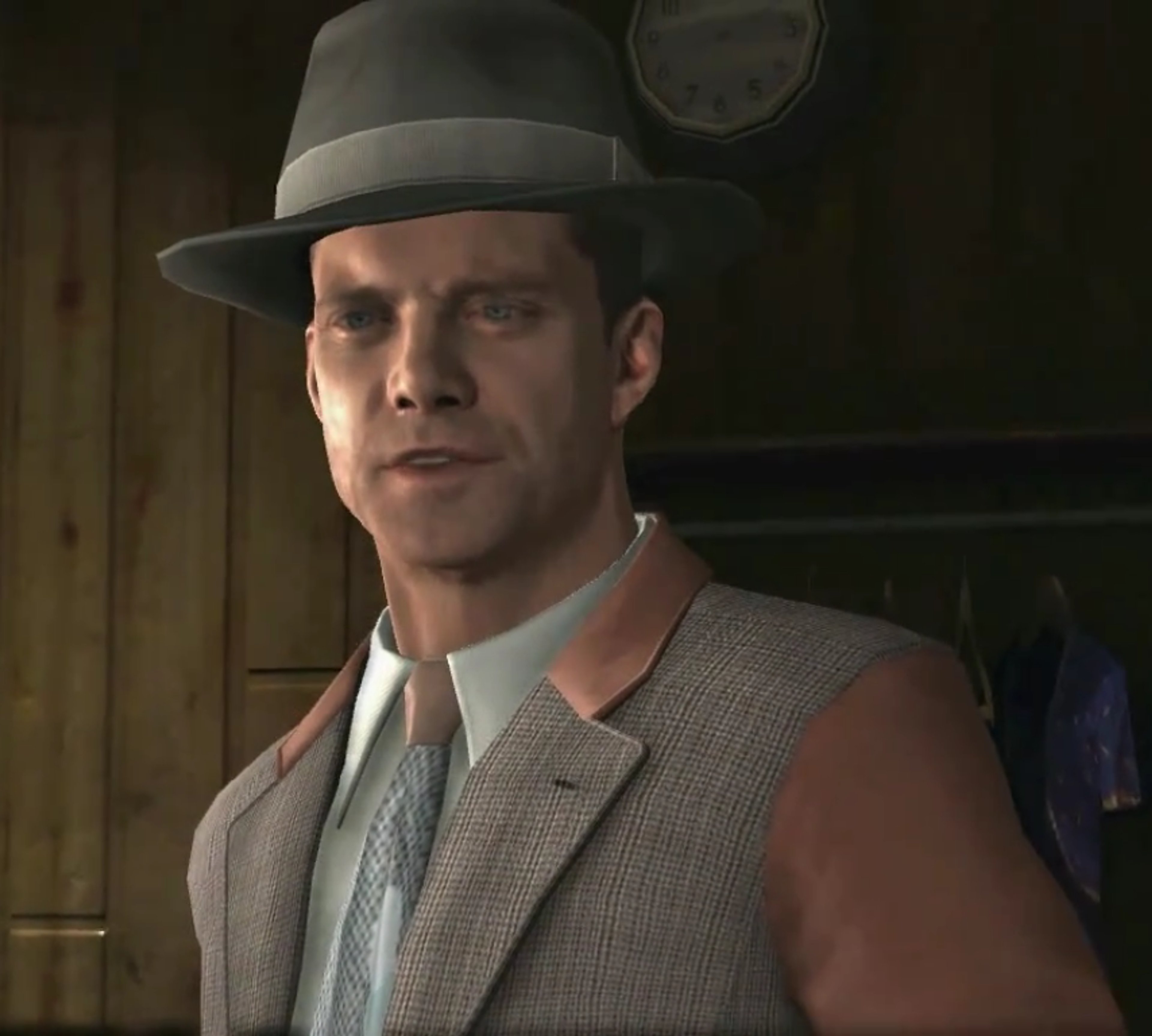 A middle-aged man in a gray suit and hat, with a stern expression