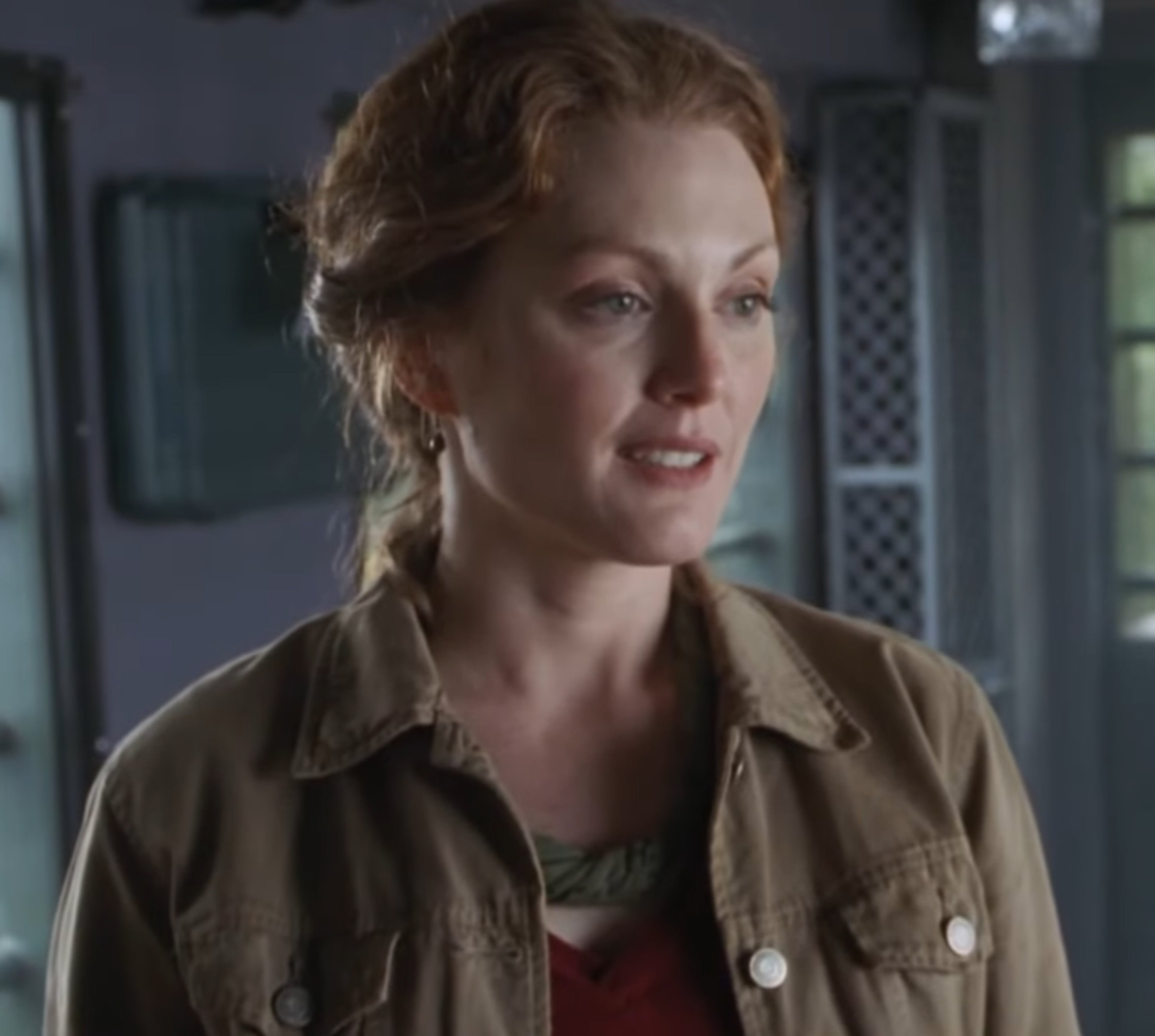 A woman with red hair wearing a khaki jacket in an outdoor setting