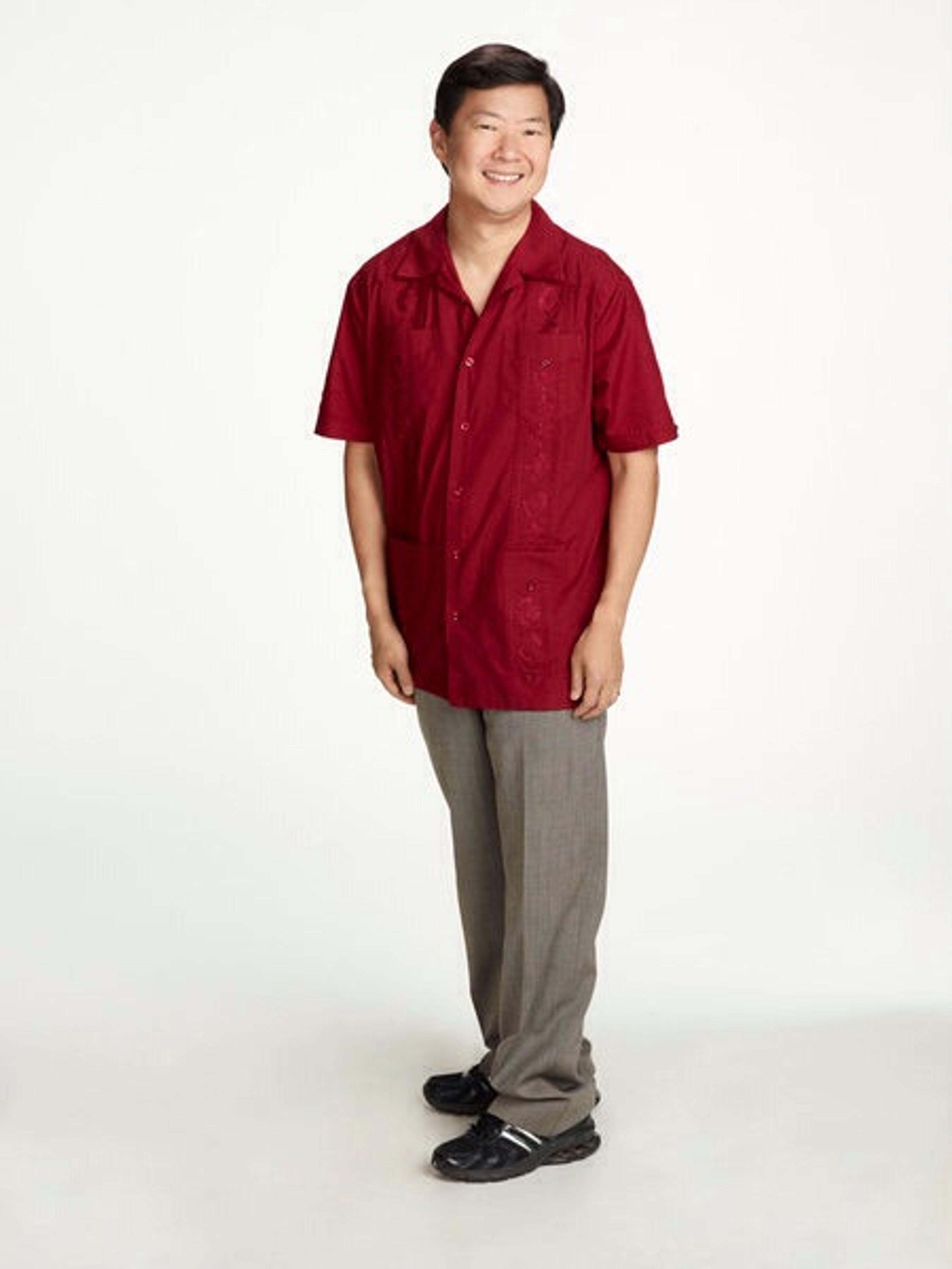 A middle-aged Asian man in a red shirt standing against a white background