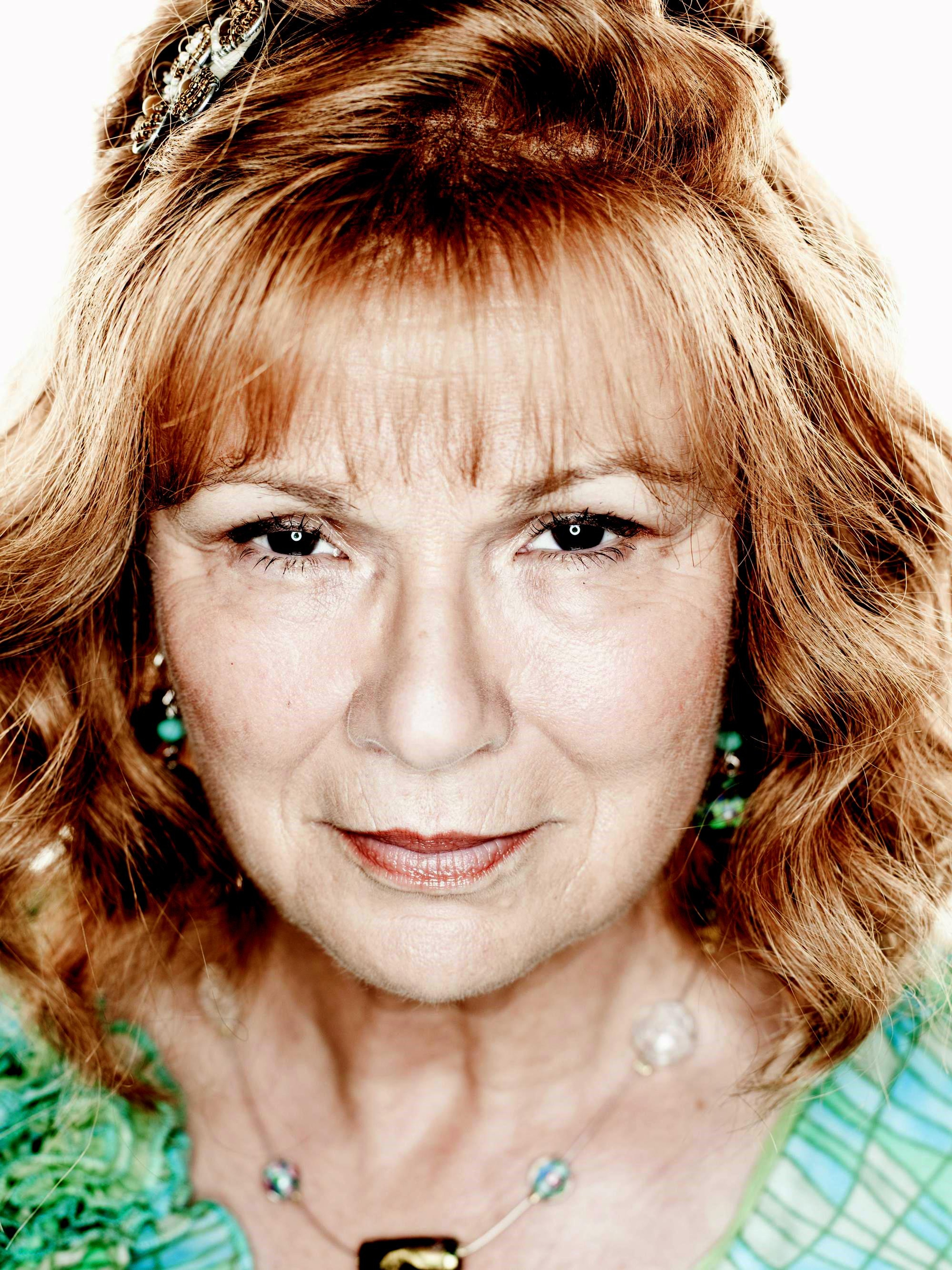 An older woman with curly red hair and a warm, friendly expression