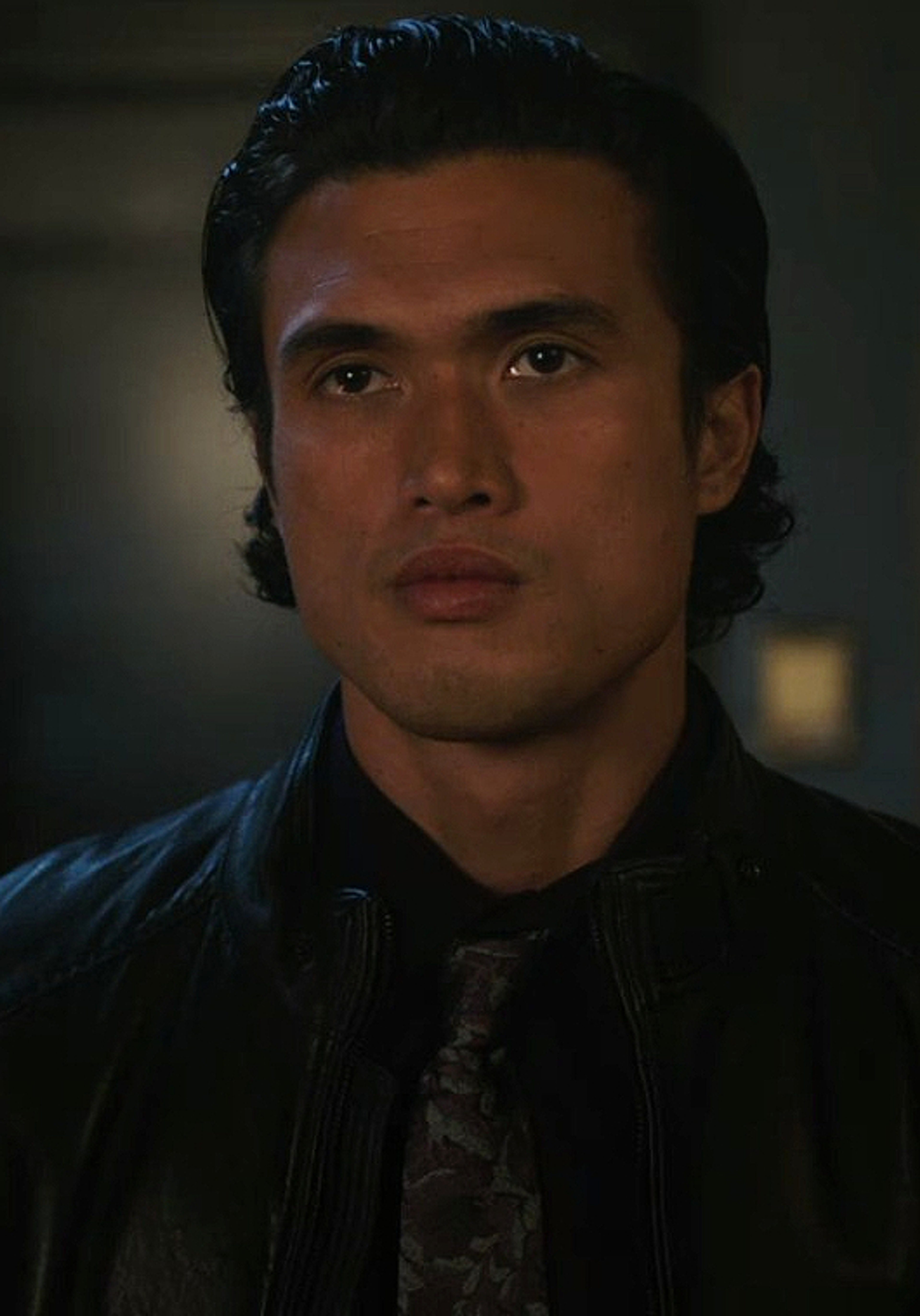 A young Asian man with a serious expression wearing a dark jacket