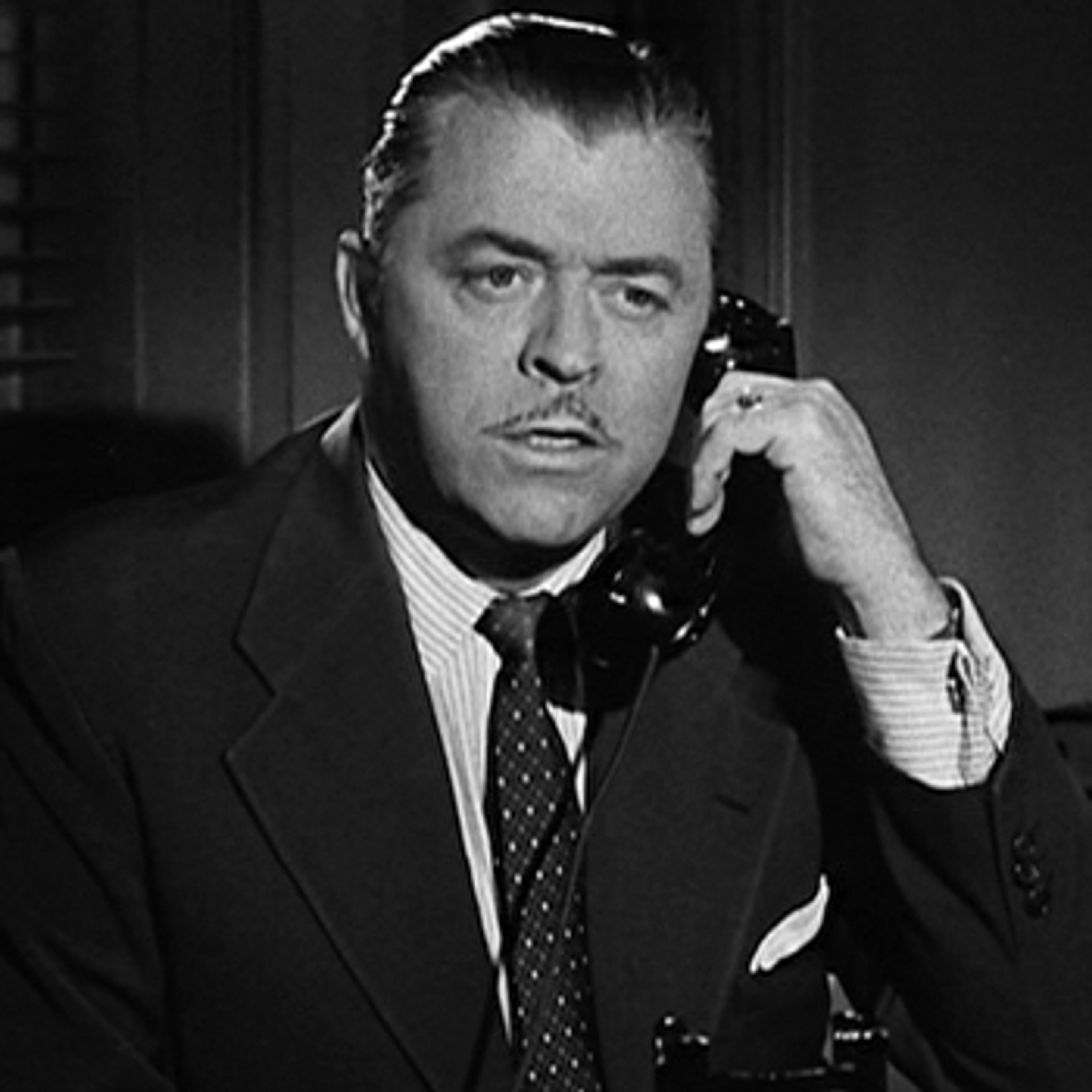 A middle-aged man in a suit speaking on a telephone
