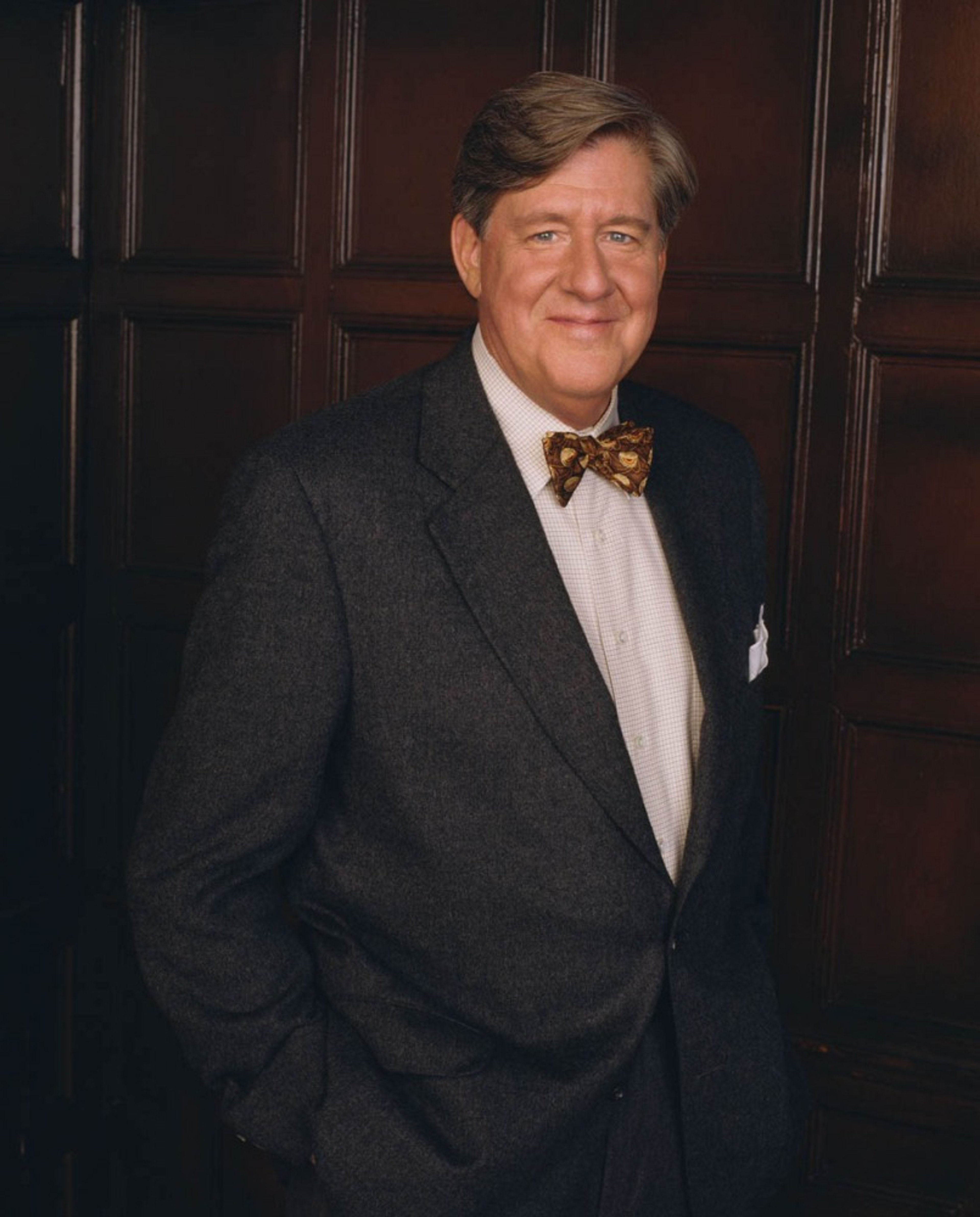 An older man in a suit and bowtie with a serious expression