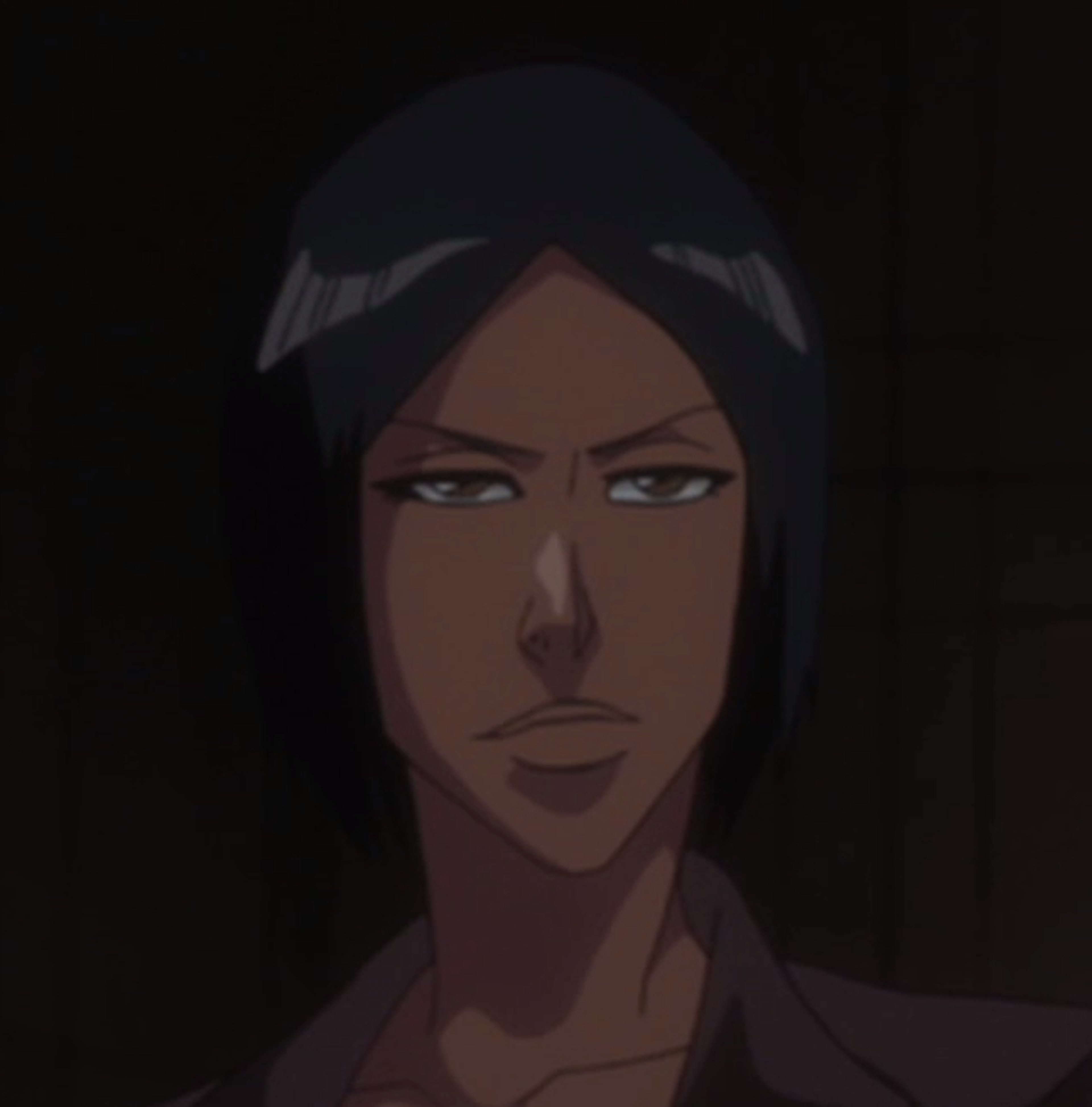A serious-looking dark-skinned woman with short dark hair