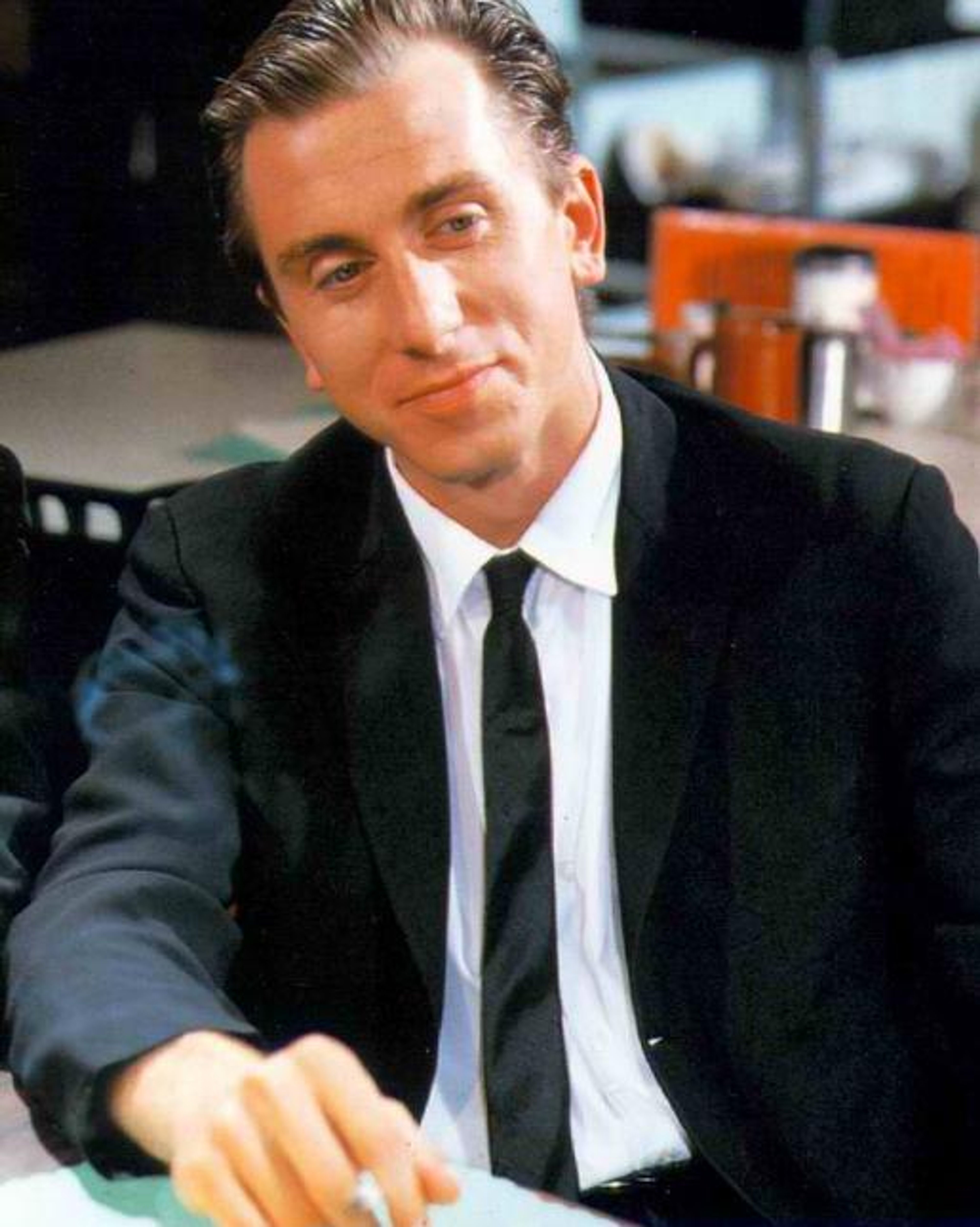 A man in a suit sitting at a desk with a serious expression