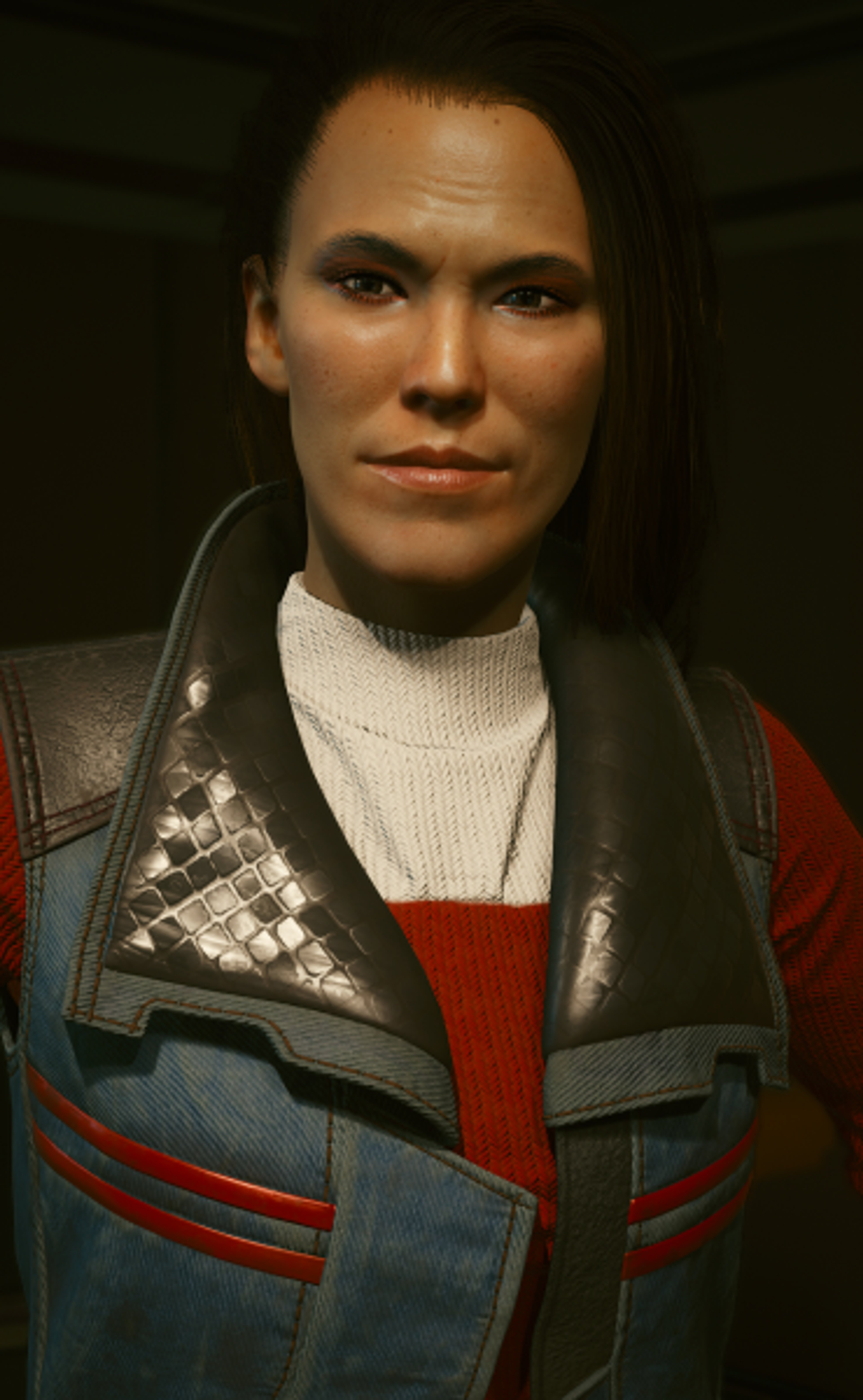 A middle-aged woman with Native American features wearing a red sweater and blue and gray jacket