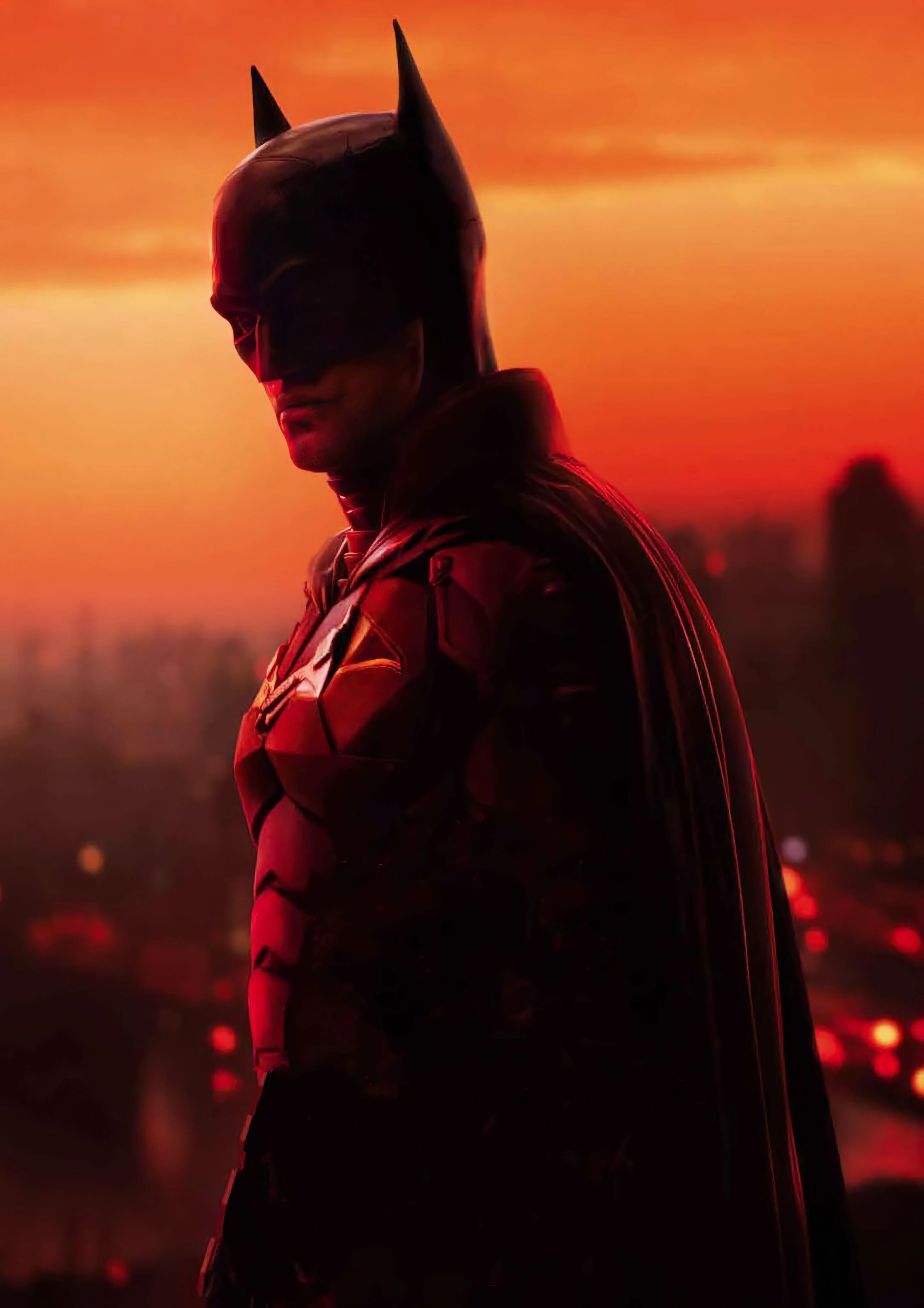A silhouetted figure in a Batman-like costume standing against an orange and red sky