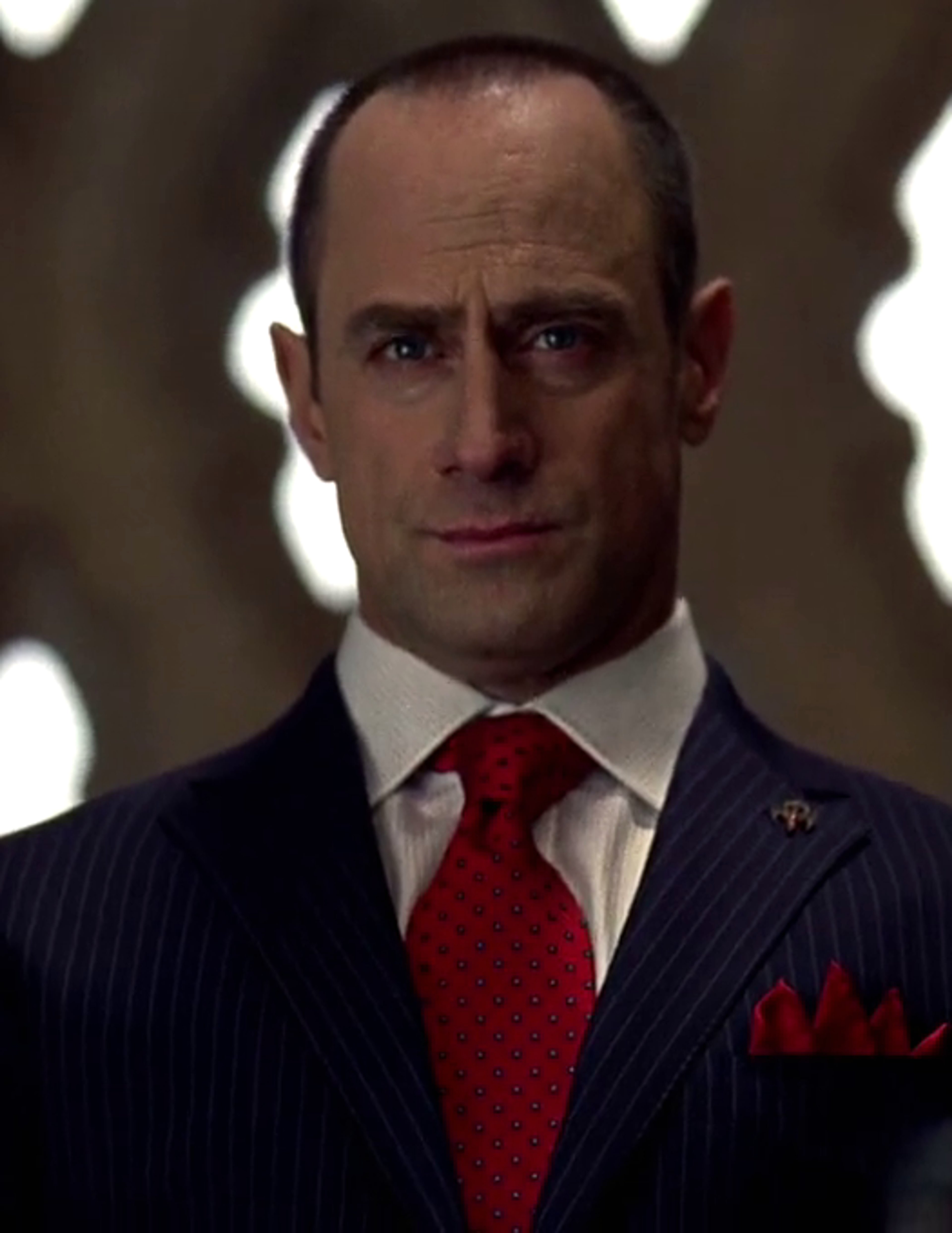 A serious-looking bald man in a suit and tie