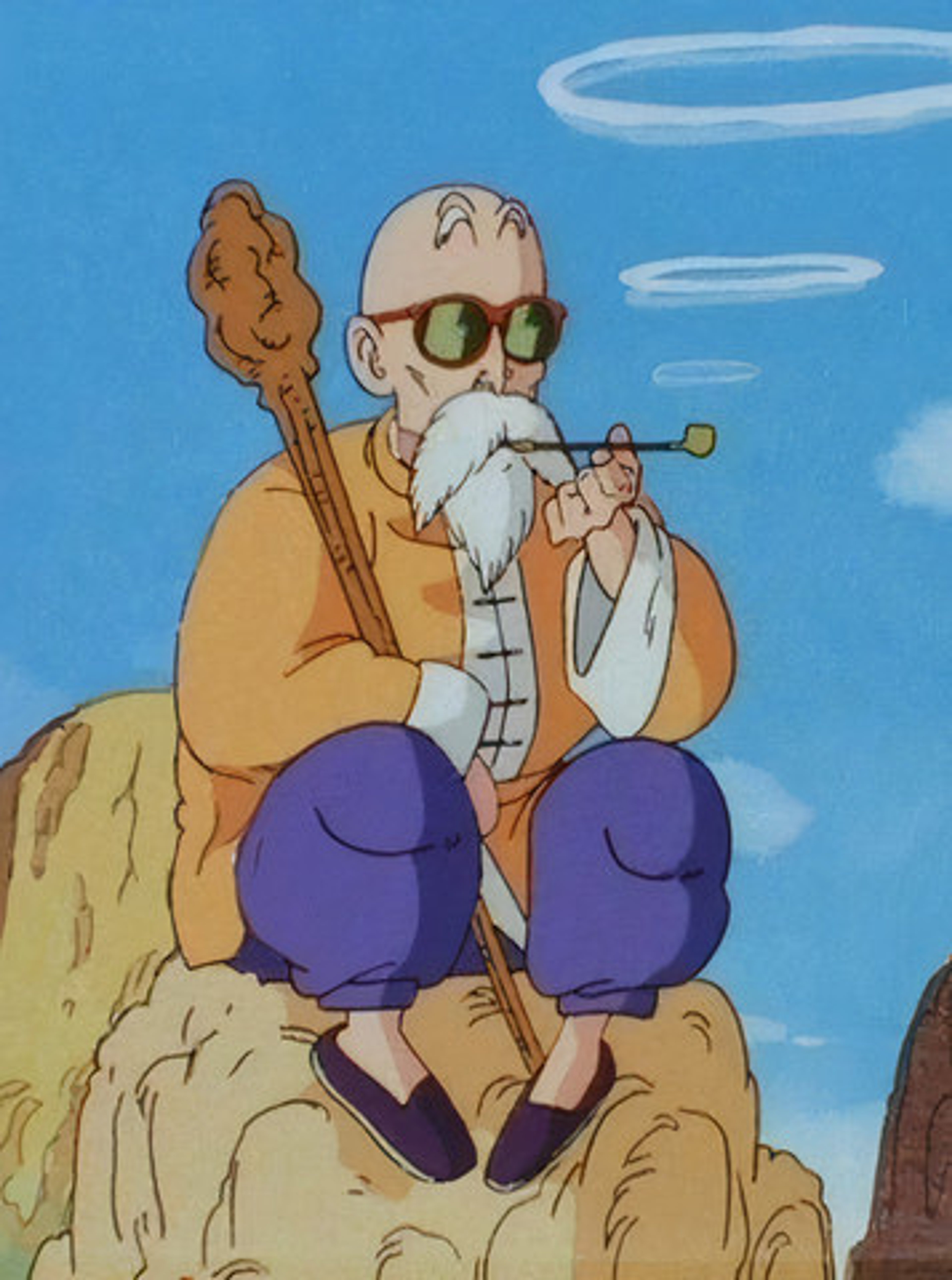 An elderly, bald man with a long white beard and sunglasses, wearing a Hawaiian shirt and sitting on a rock formation.