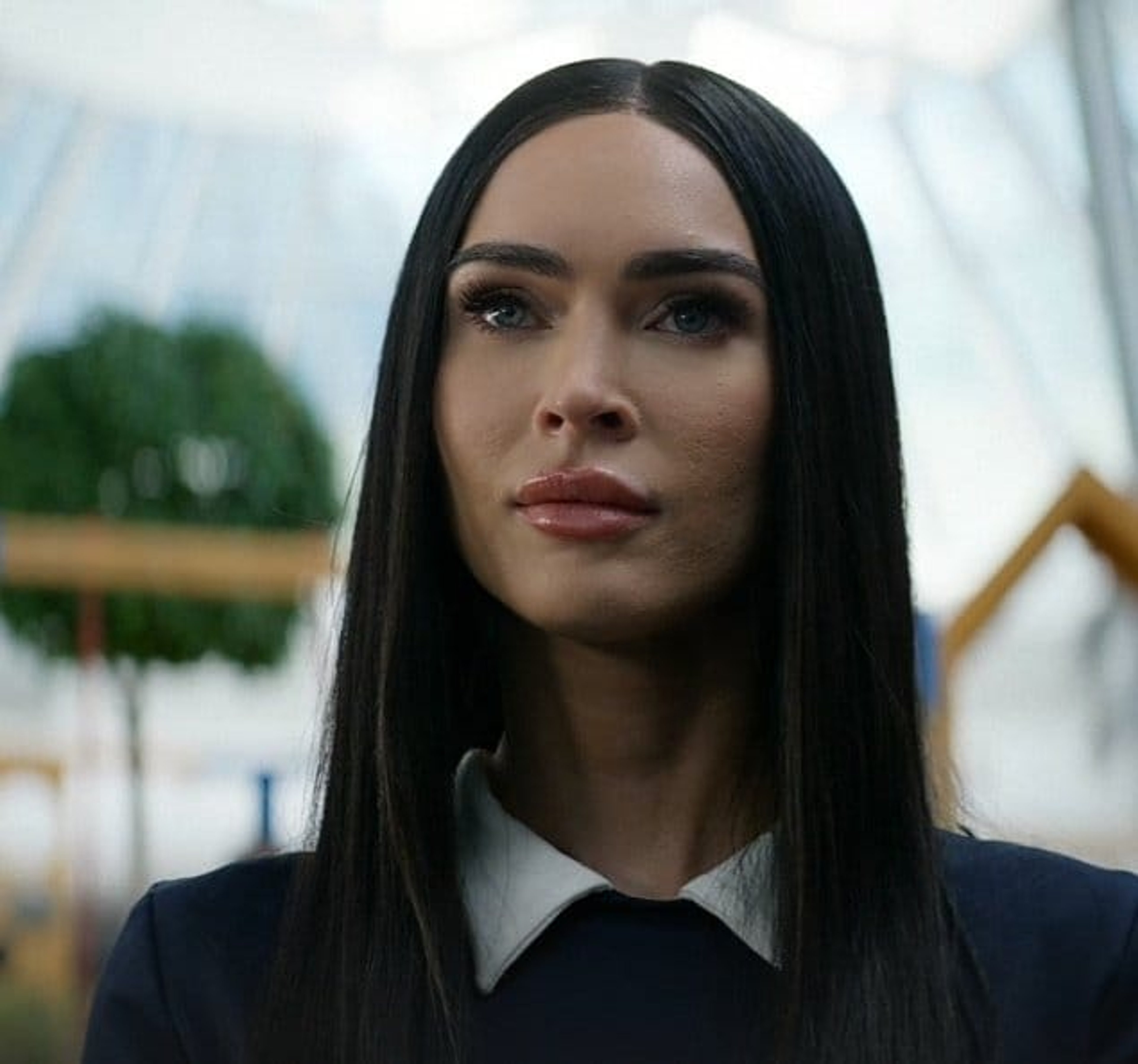 A woman with long dark hair wearing a black suit, looking serious and intense.